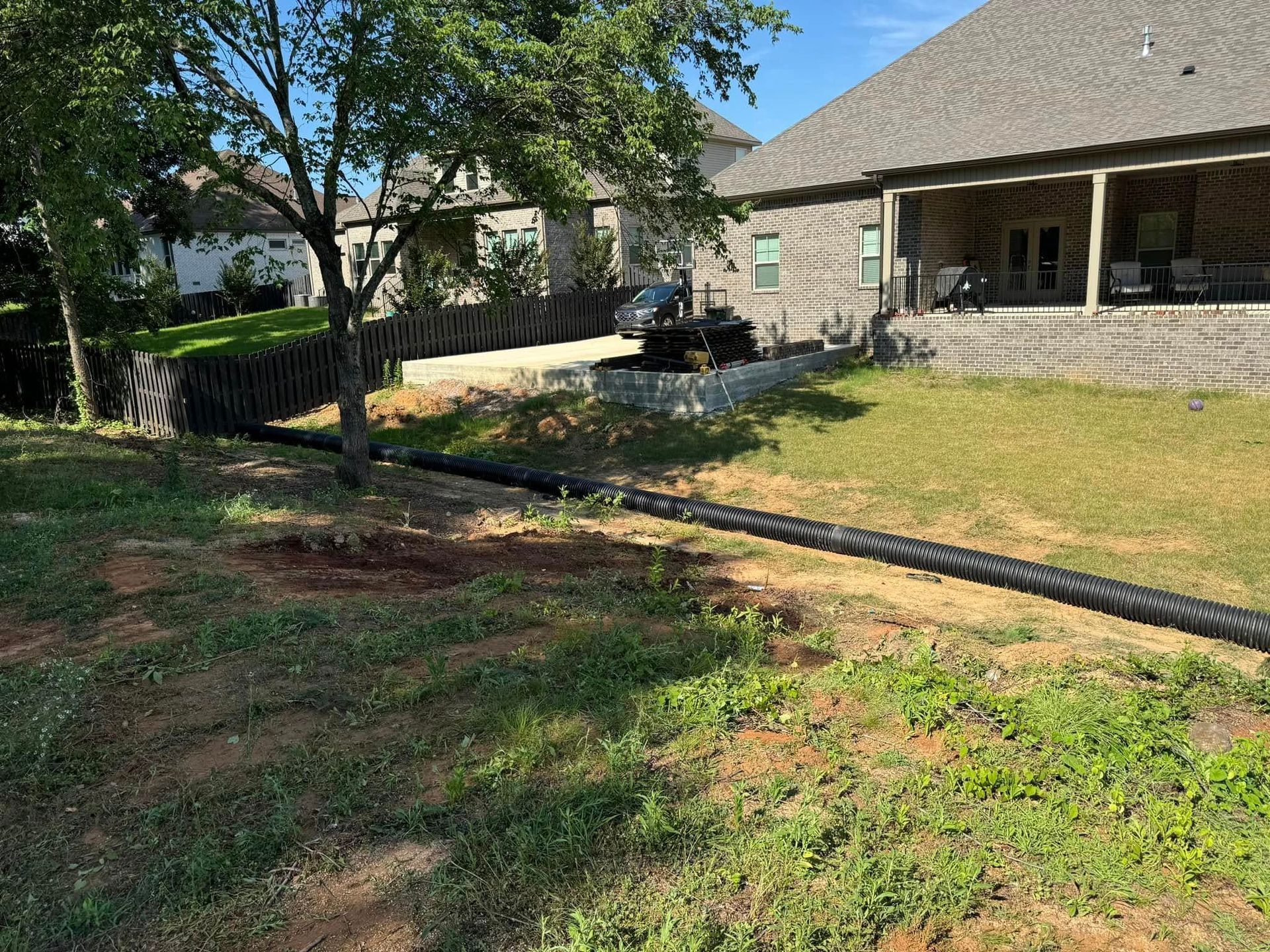 A large hose is laying in the grass in front of a house.