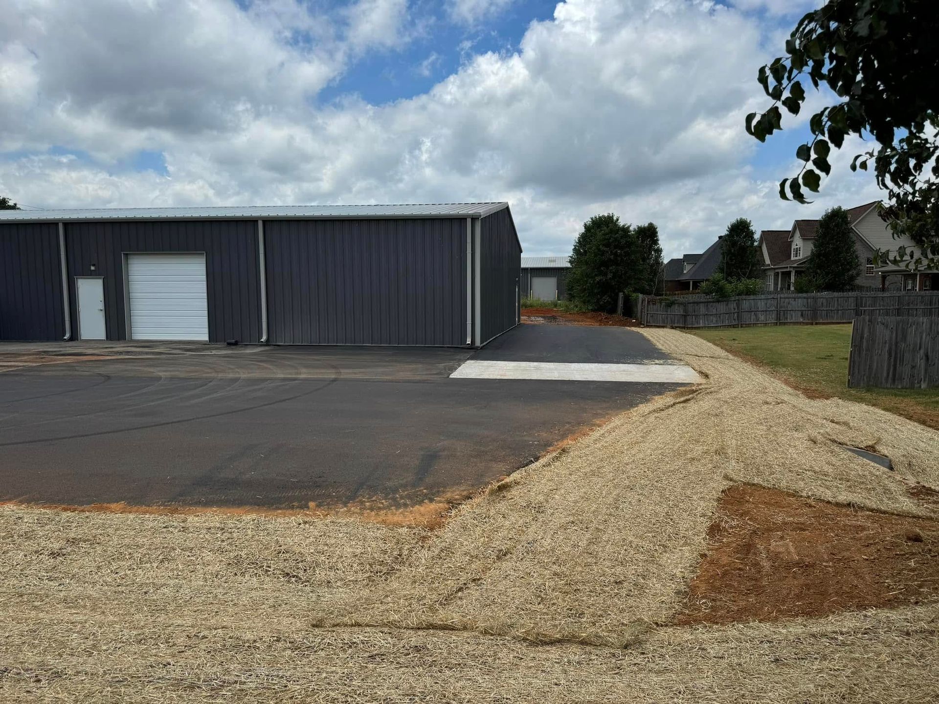 A large building with a garage door is sitting on top of a gravel lot.