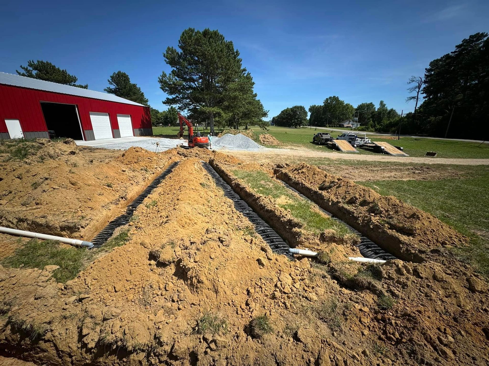 A dirt field with a red barn in the background.
