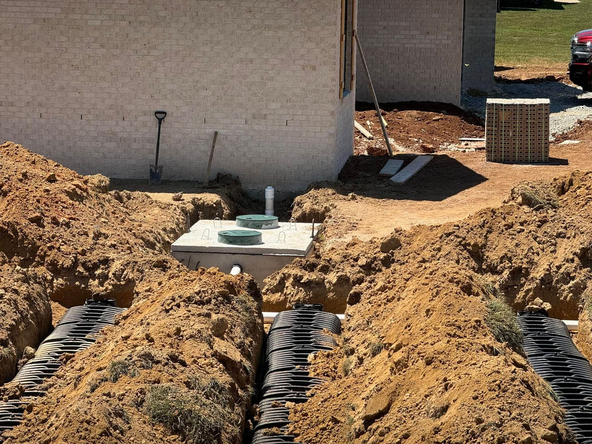 A septic system is being installed in the dirt in front of a house