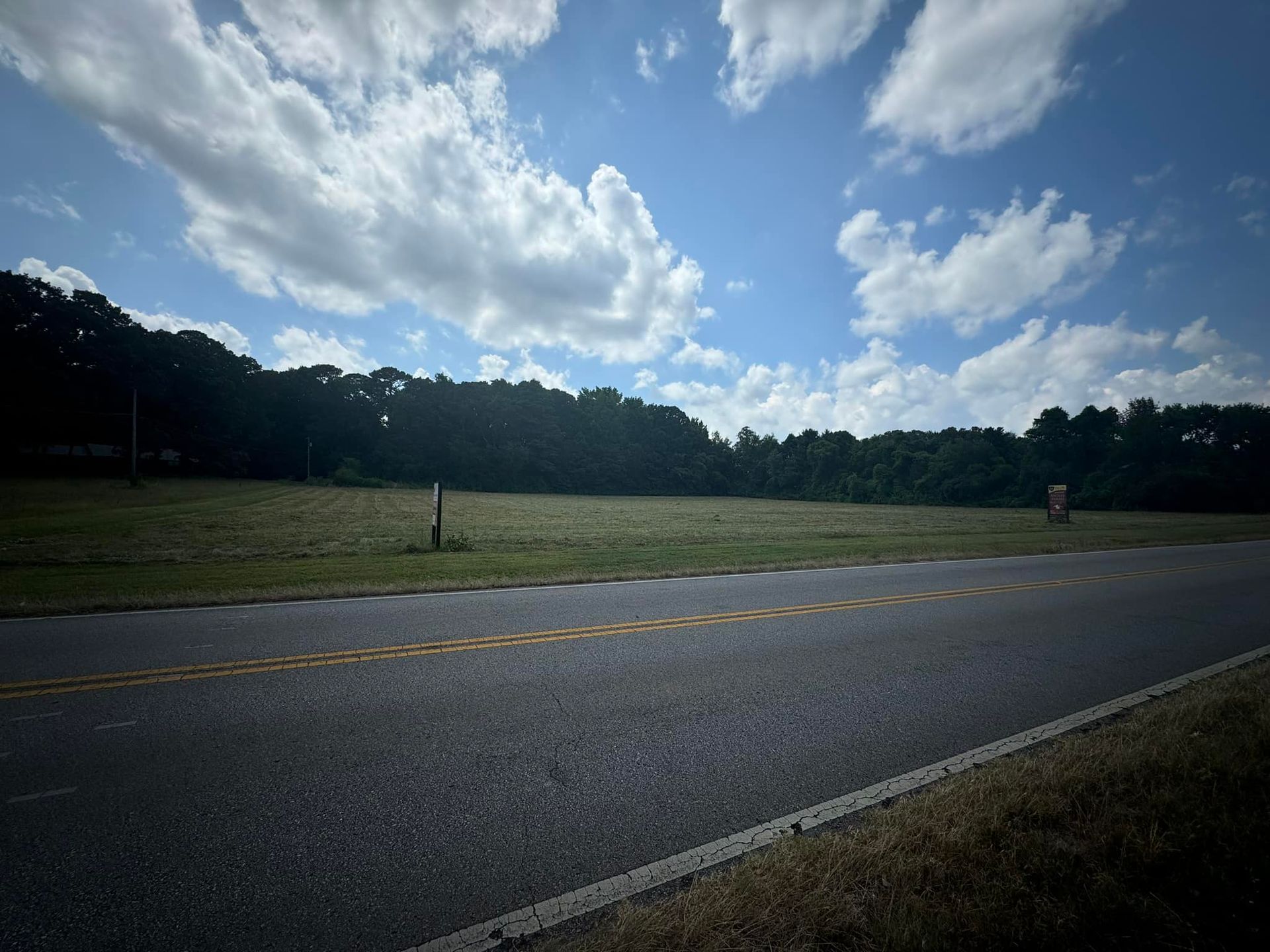 A road going through a field with trees in the background