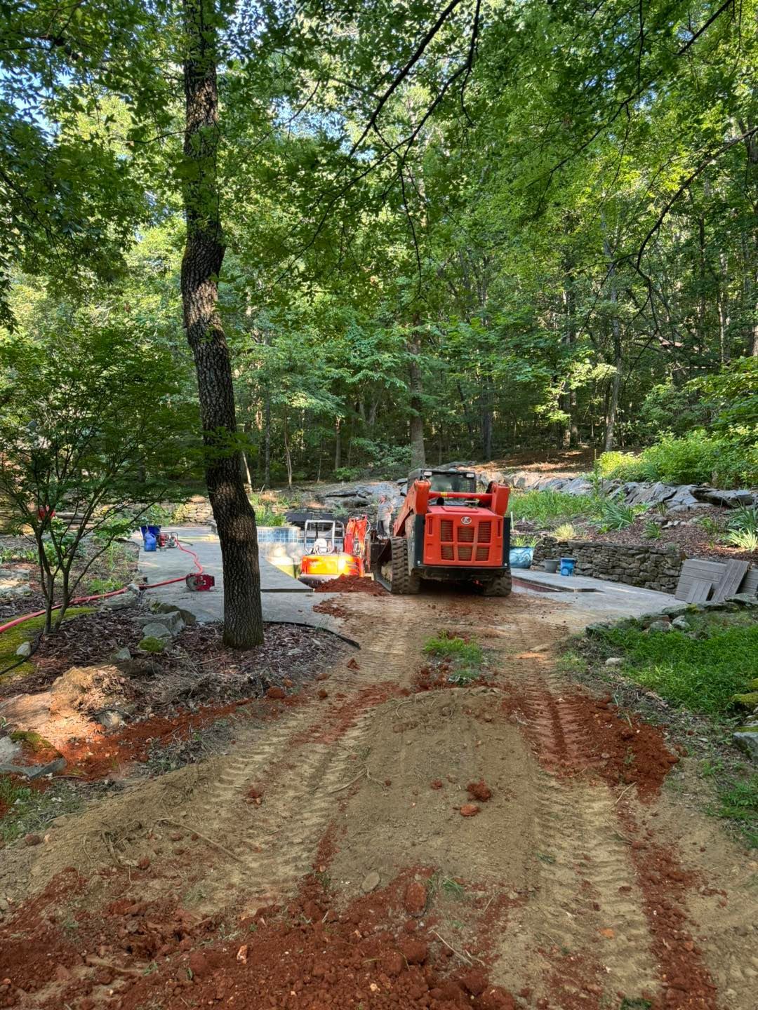 A tractor is driving down a dirt road in the woods.