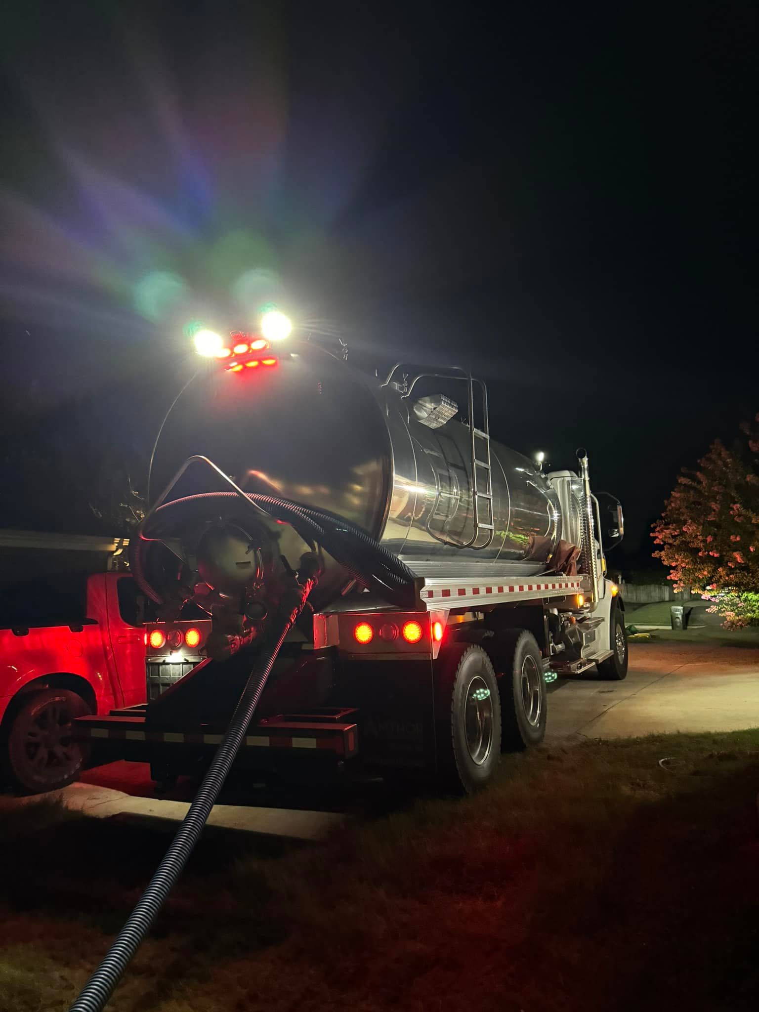 A vacuum truck is parked on the side of the road at night.