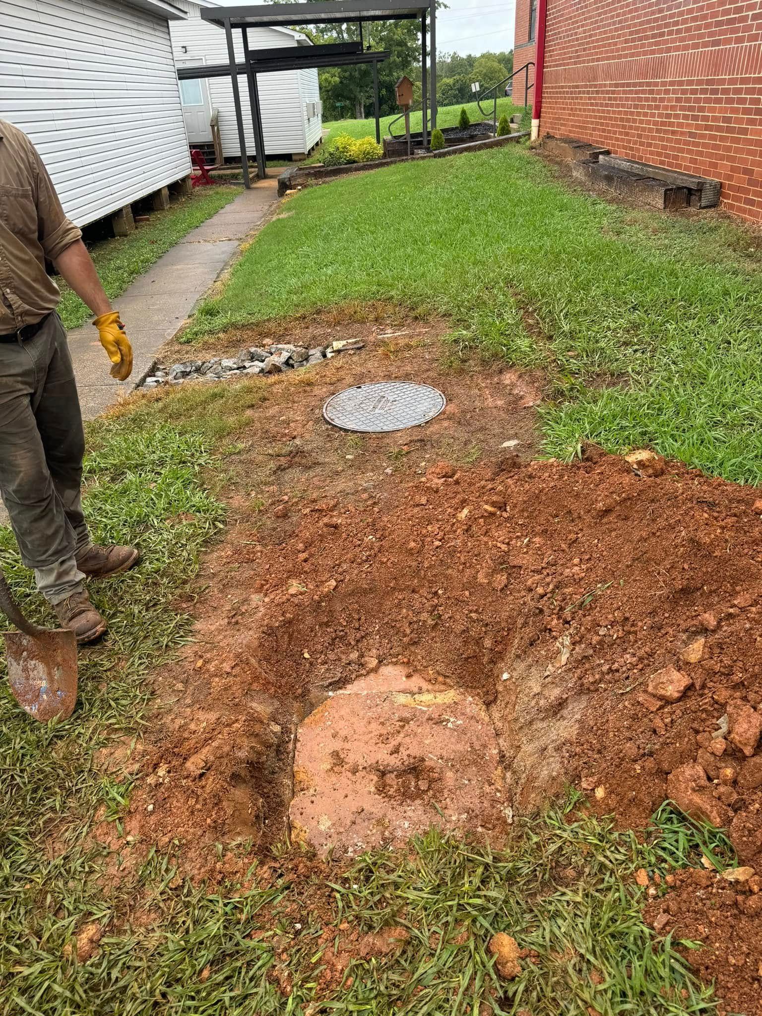 A man is digging a hole in the ground in front of a house.