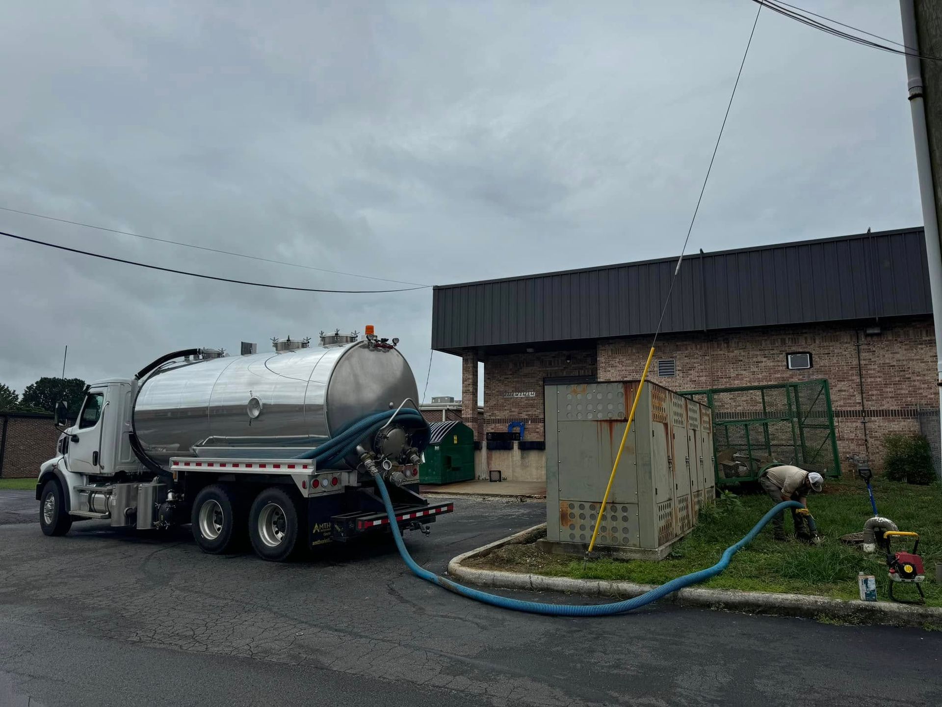 A vacuum truck is being filled with water in front of a building.