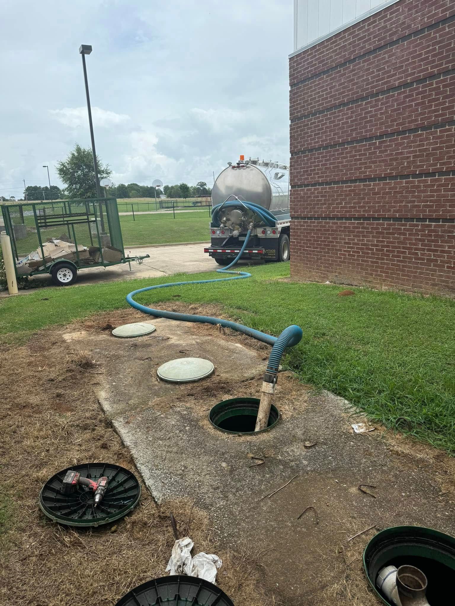 A tanker truck is pumping water into a septic tank.
