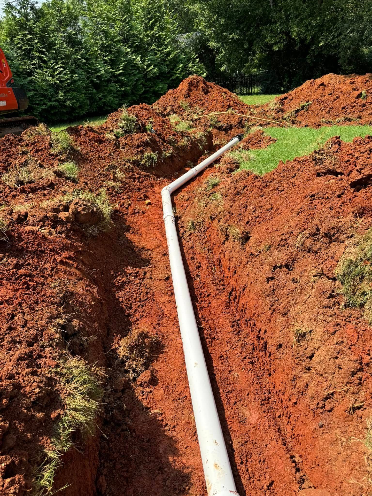 A white pipe is being installed in the dirt.