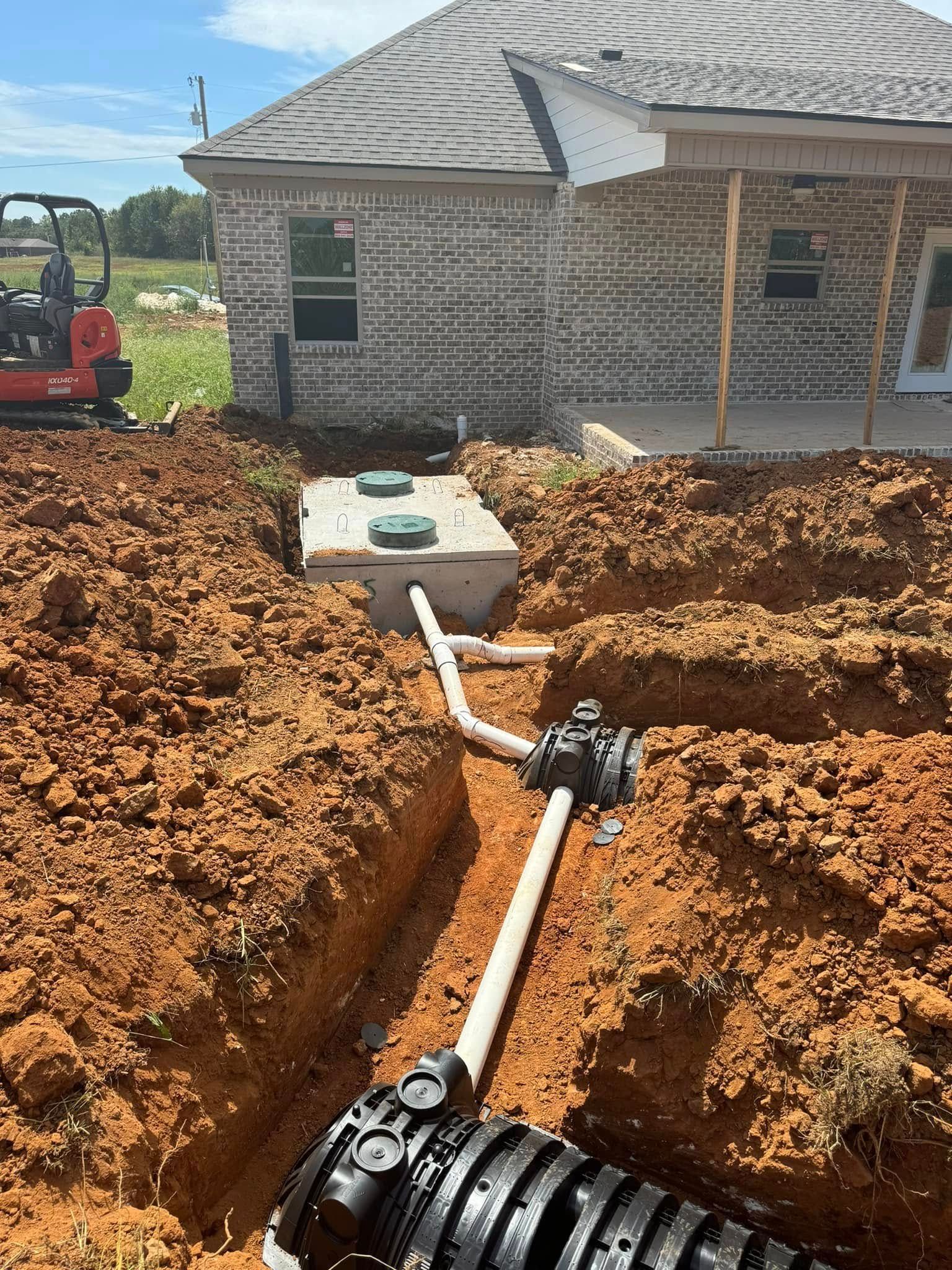 A septic tank is being installed in the dirt in front of a house.
