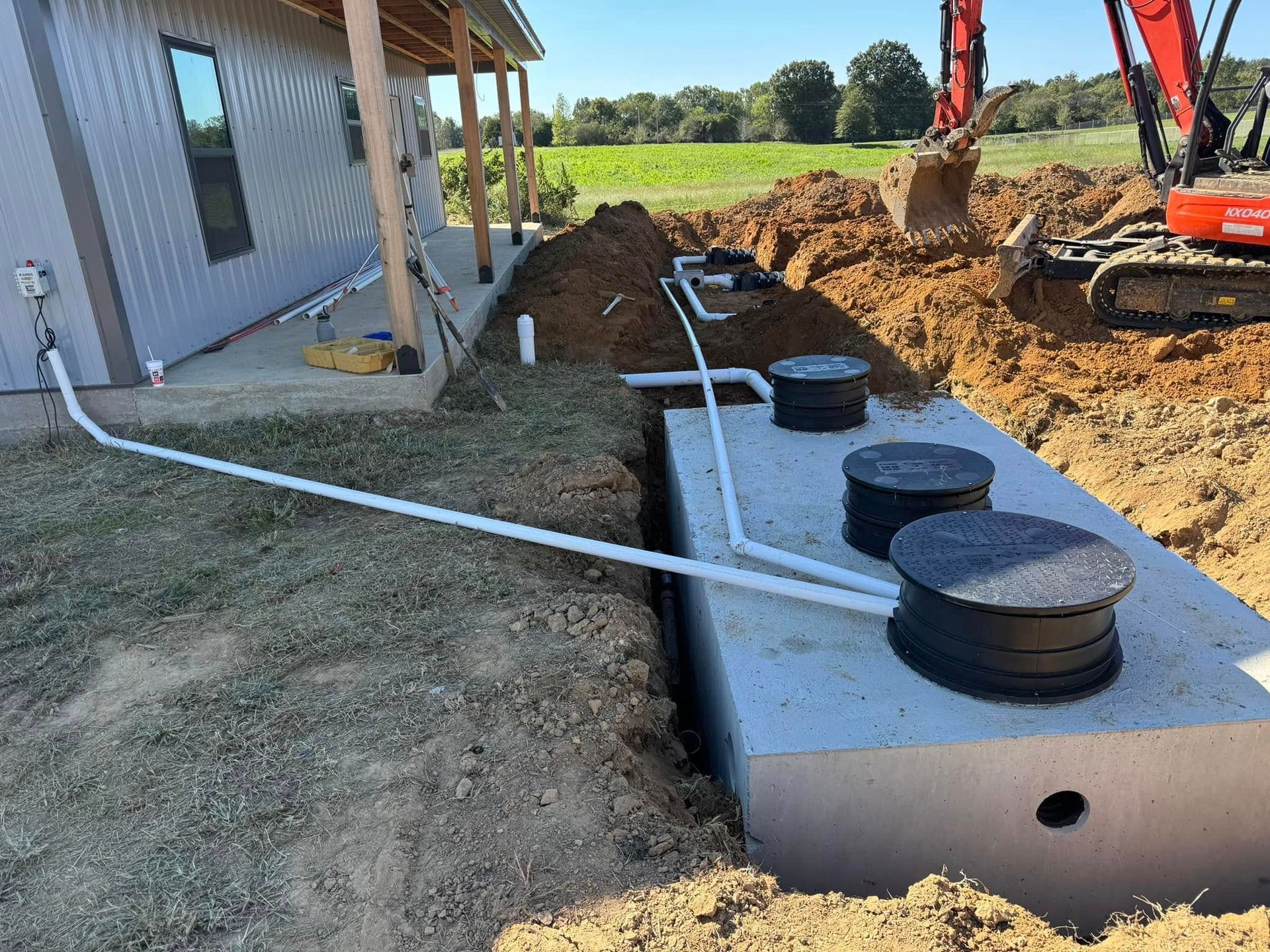 A septic tank is being installed in the dirt in front of a house.