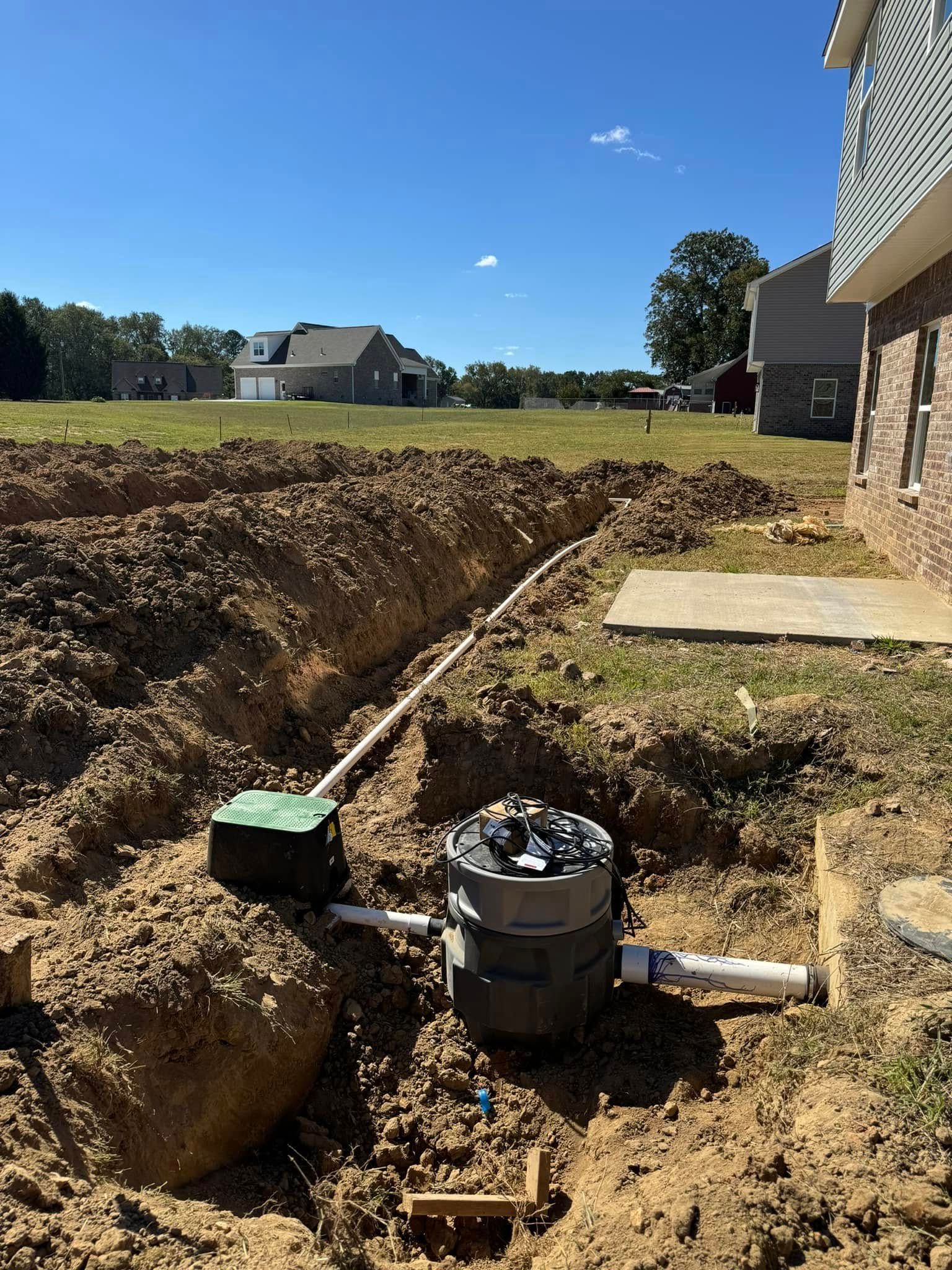 A septic tank is being installed in the dirt in front of a house.
