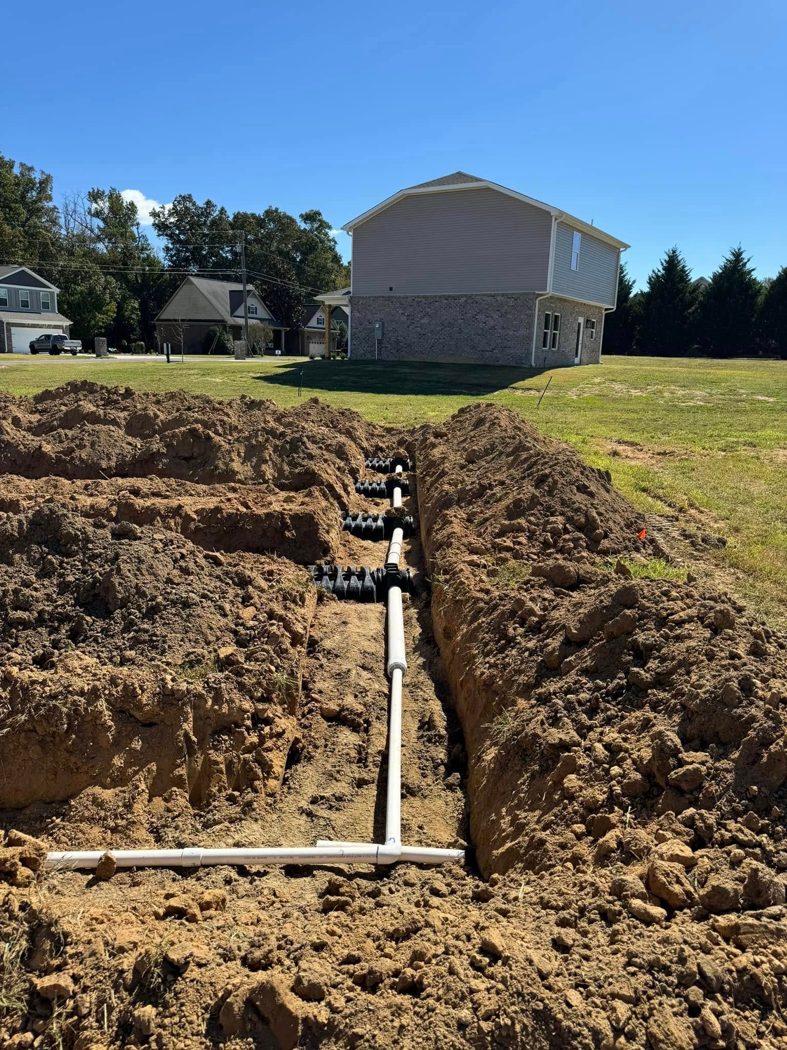 A pipe is being installed in the dirt in front of a house.