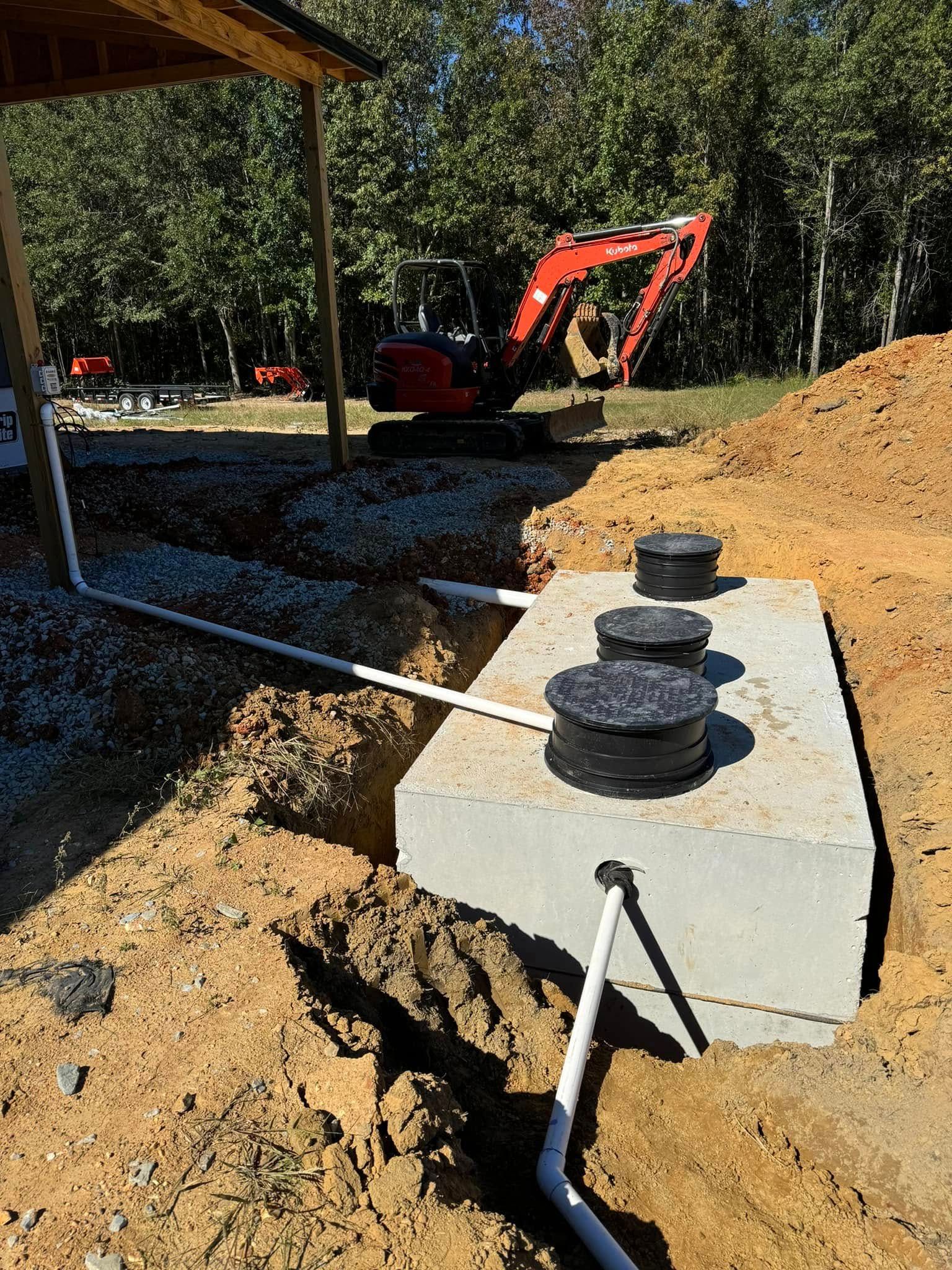 A concrete septic tank is being installed in a dirt field.