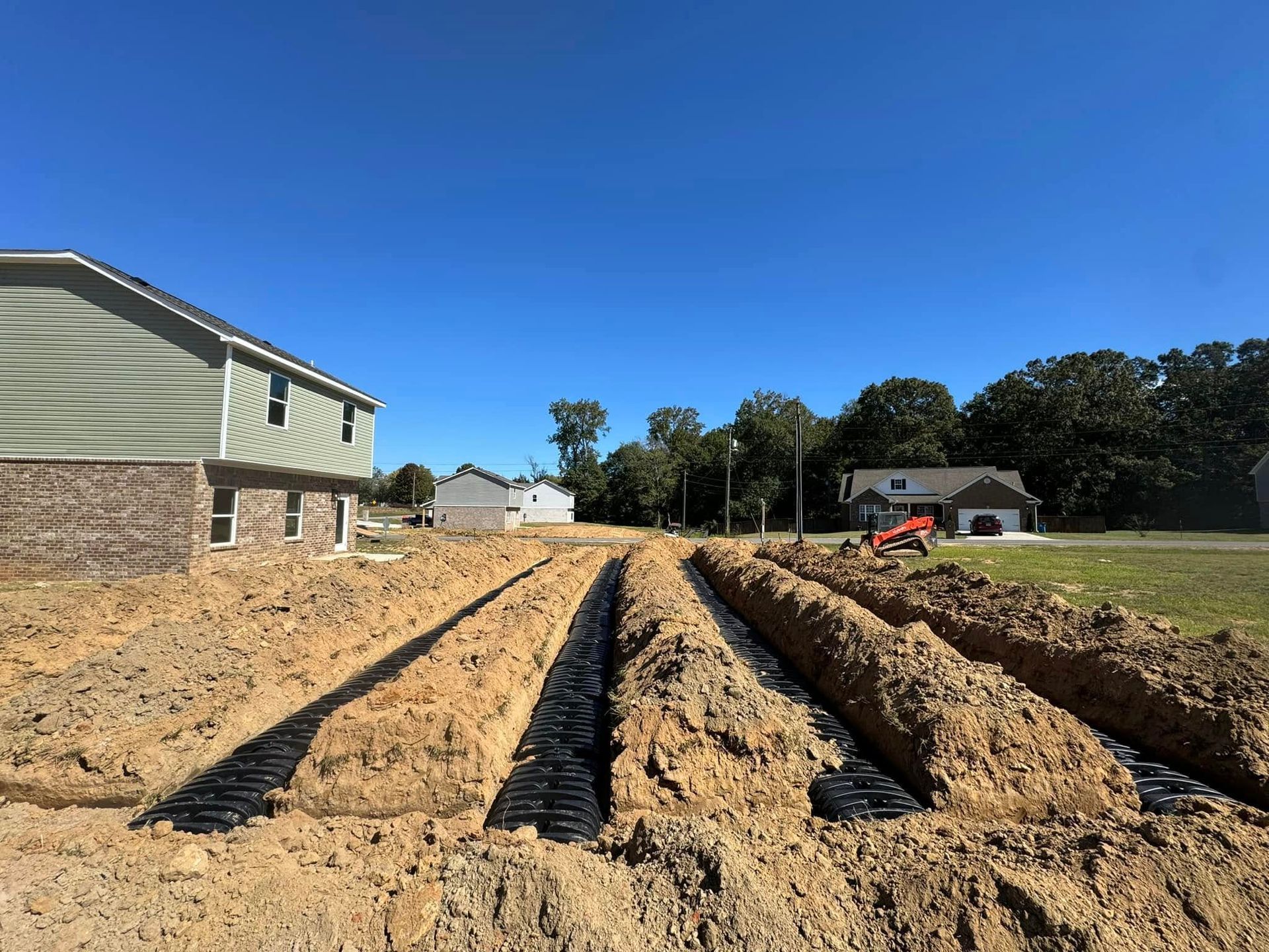 A large dirt field with a house in the background.