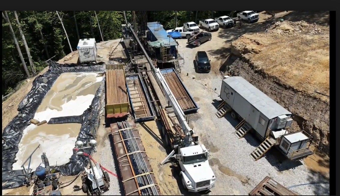 Construction site with concrete foundations, cranes, trucks, and workers on a dirt lot.