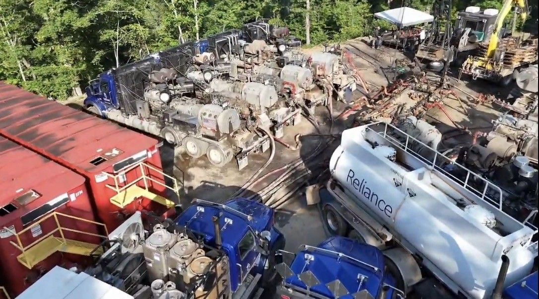 Aerial view of a tanker truck yard with red, blue, and white fuel trucks parked closely together.