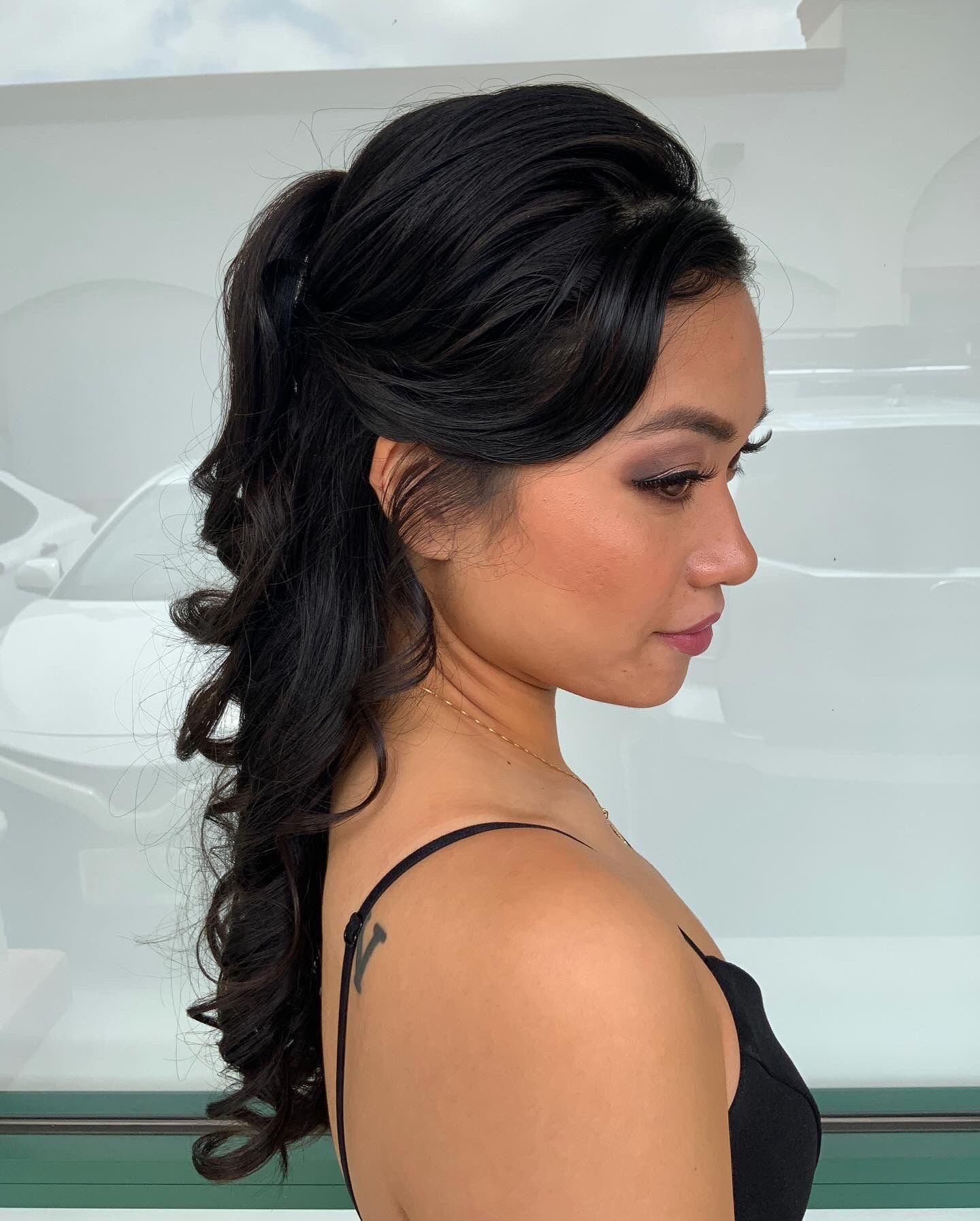 A woman with long black hair is wearing a black tank top.