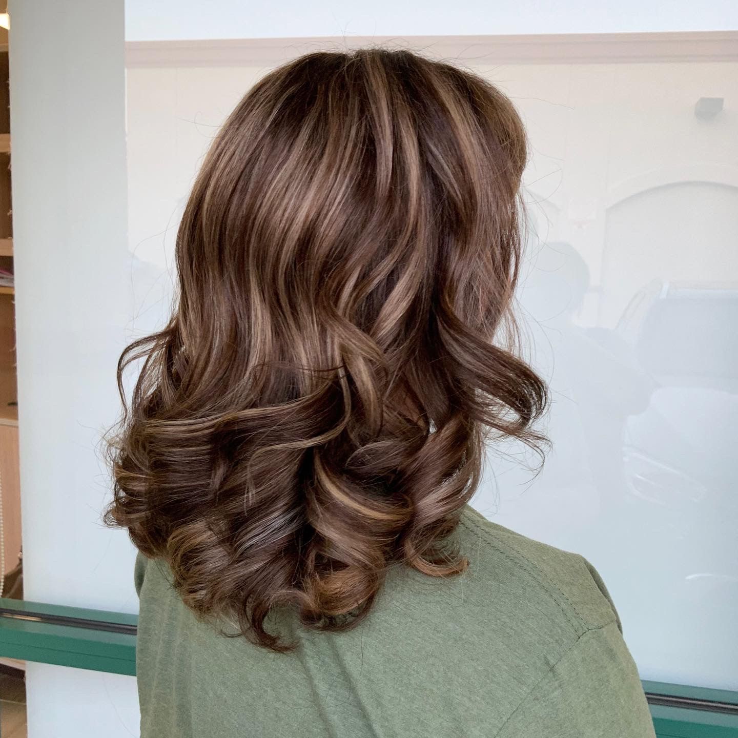 A woman with long brown hair is wearing a green shirt.
