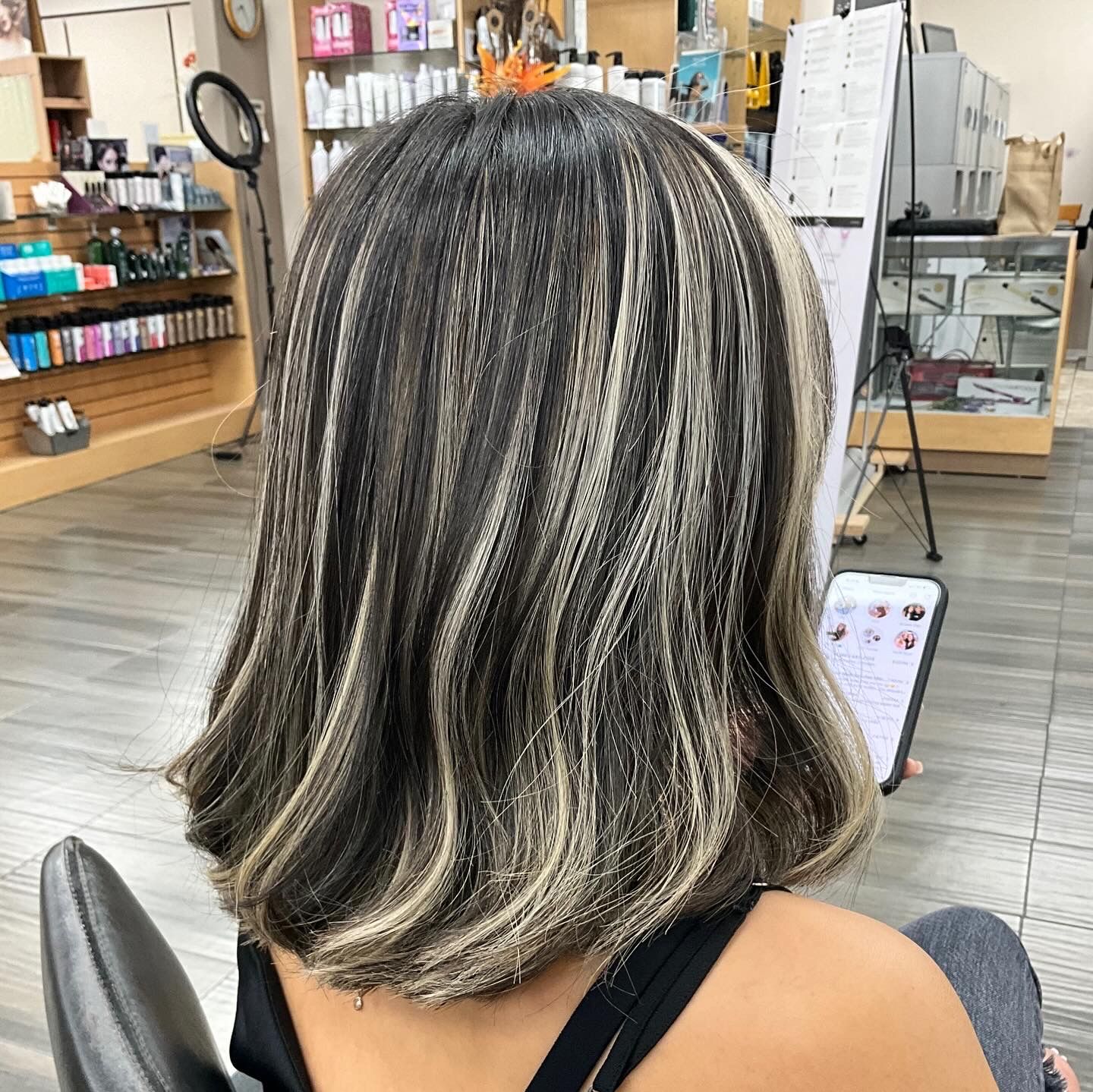 A woman is sitting in a chair in a salon with her back to the camera.