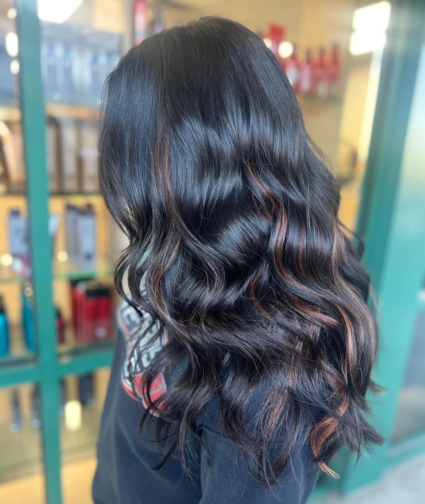 A woman with long black hair is standing in front of a store.