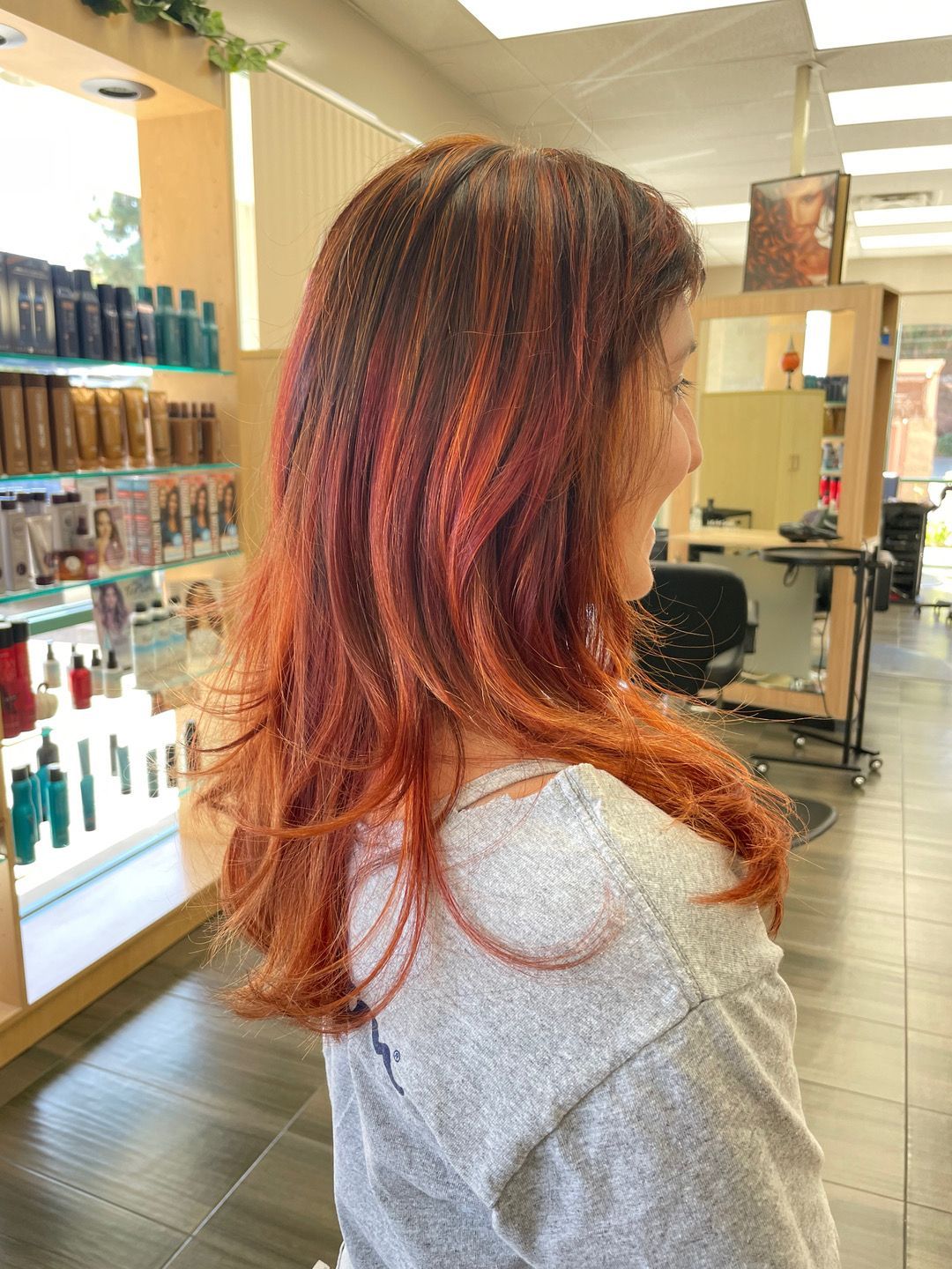 A woman with long red hair is standing in a salon.