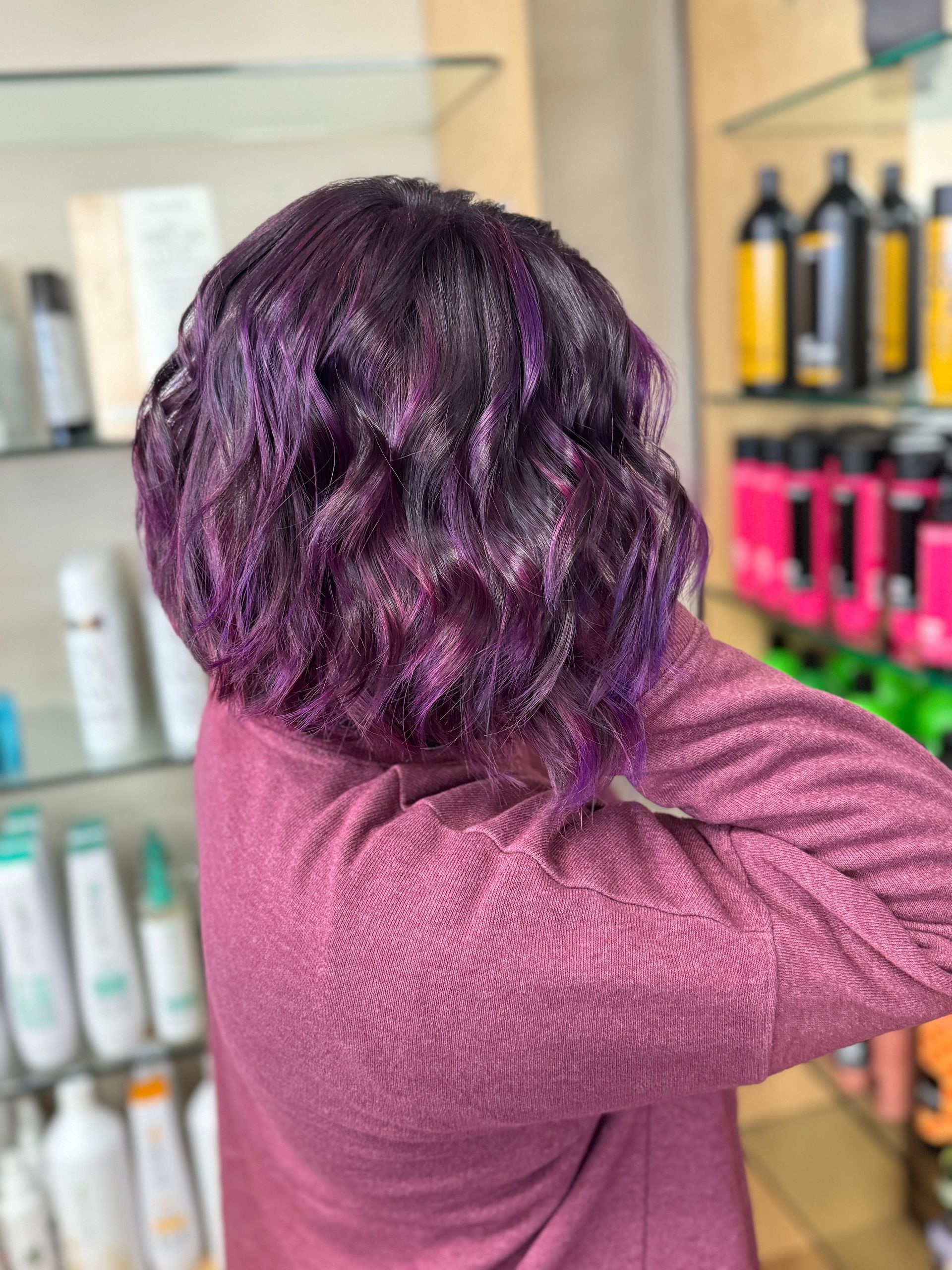 A woman with purple hair is standing in a salon.