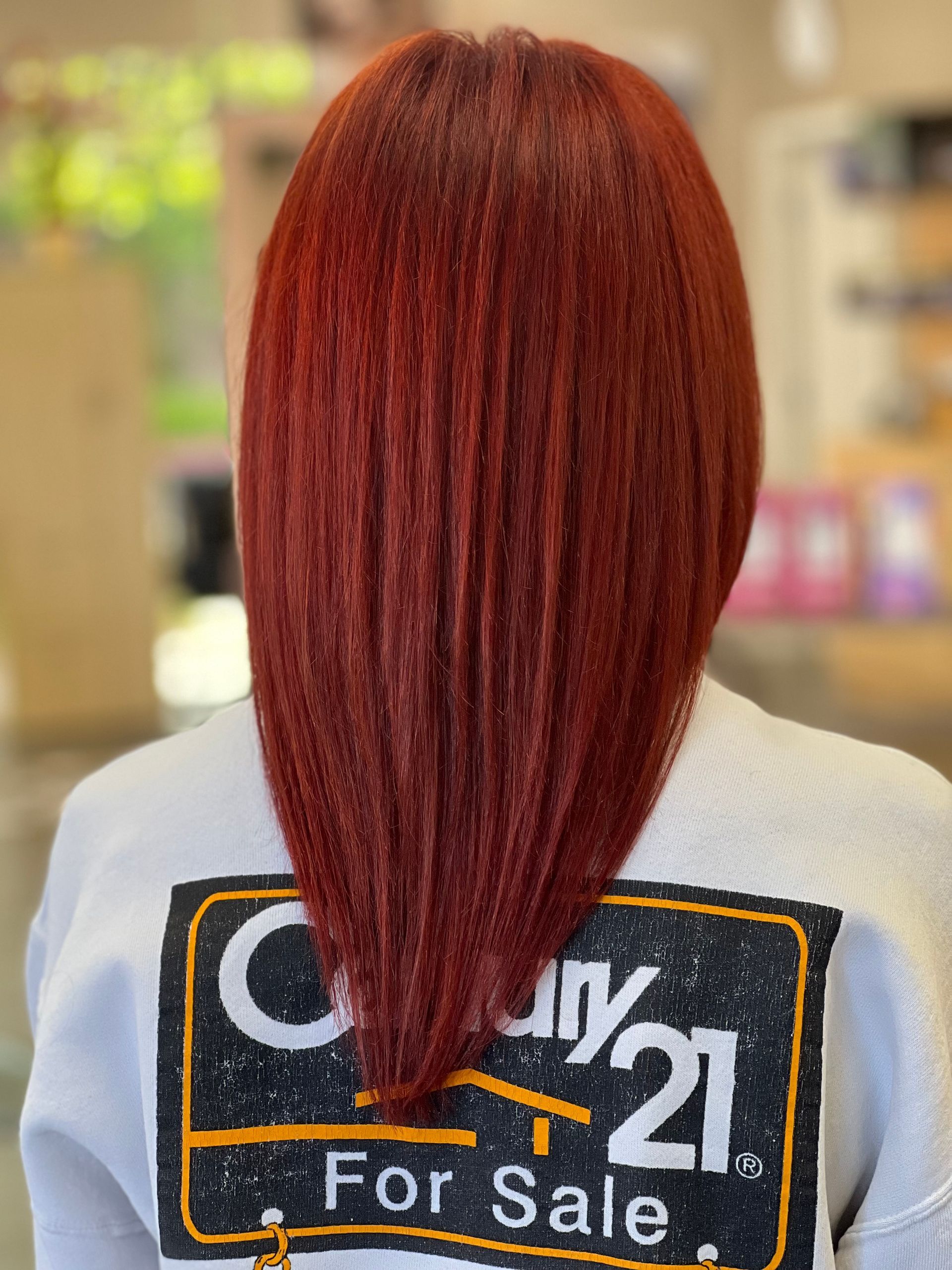 A woman with red hair is wearing a century 21 for sale shirt.