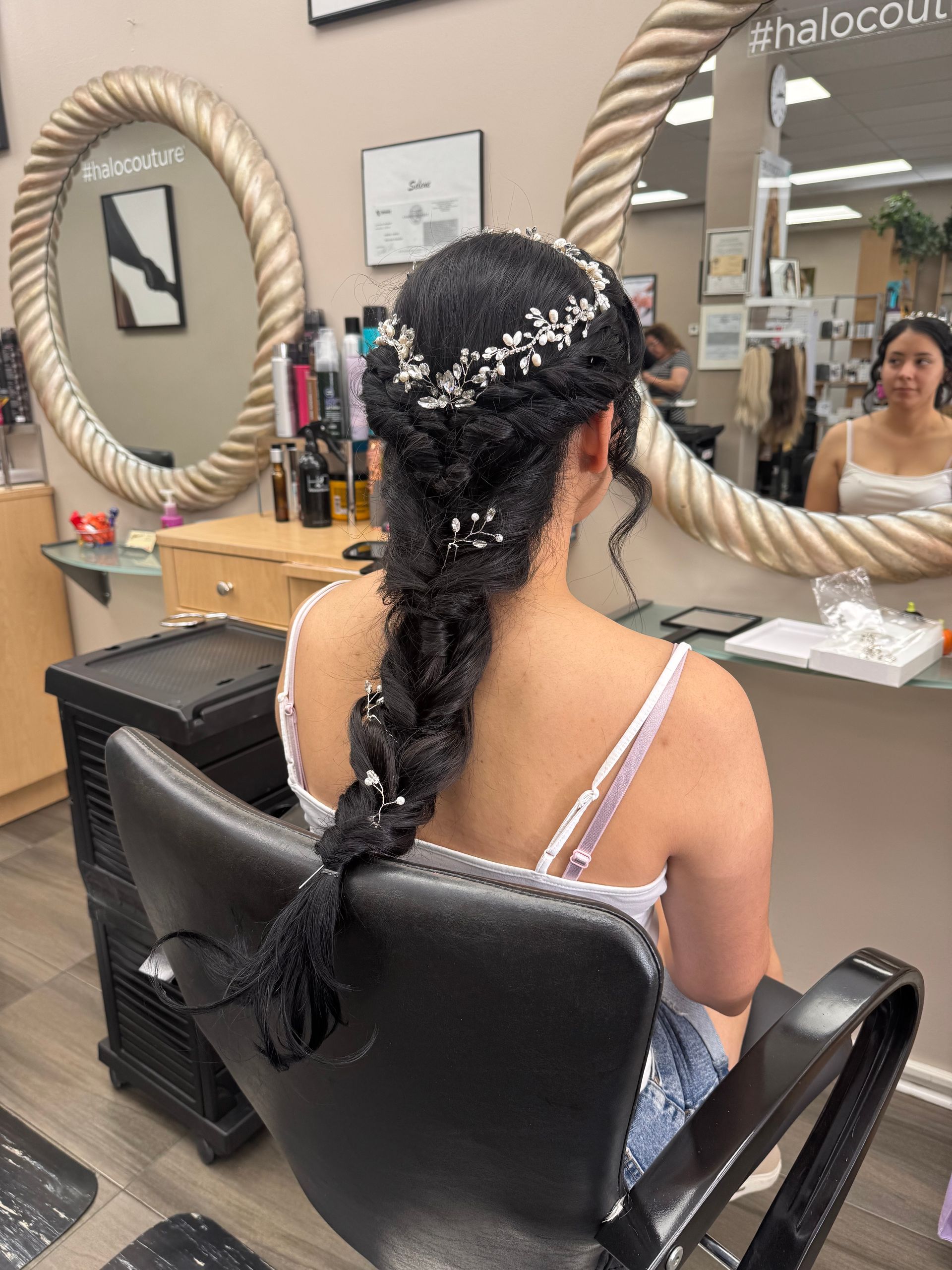 A woman is sitting in a chair in a salon with her hair in a braid.