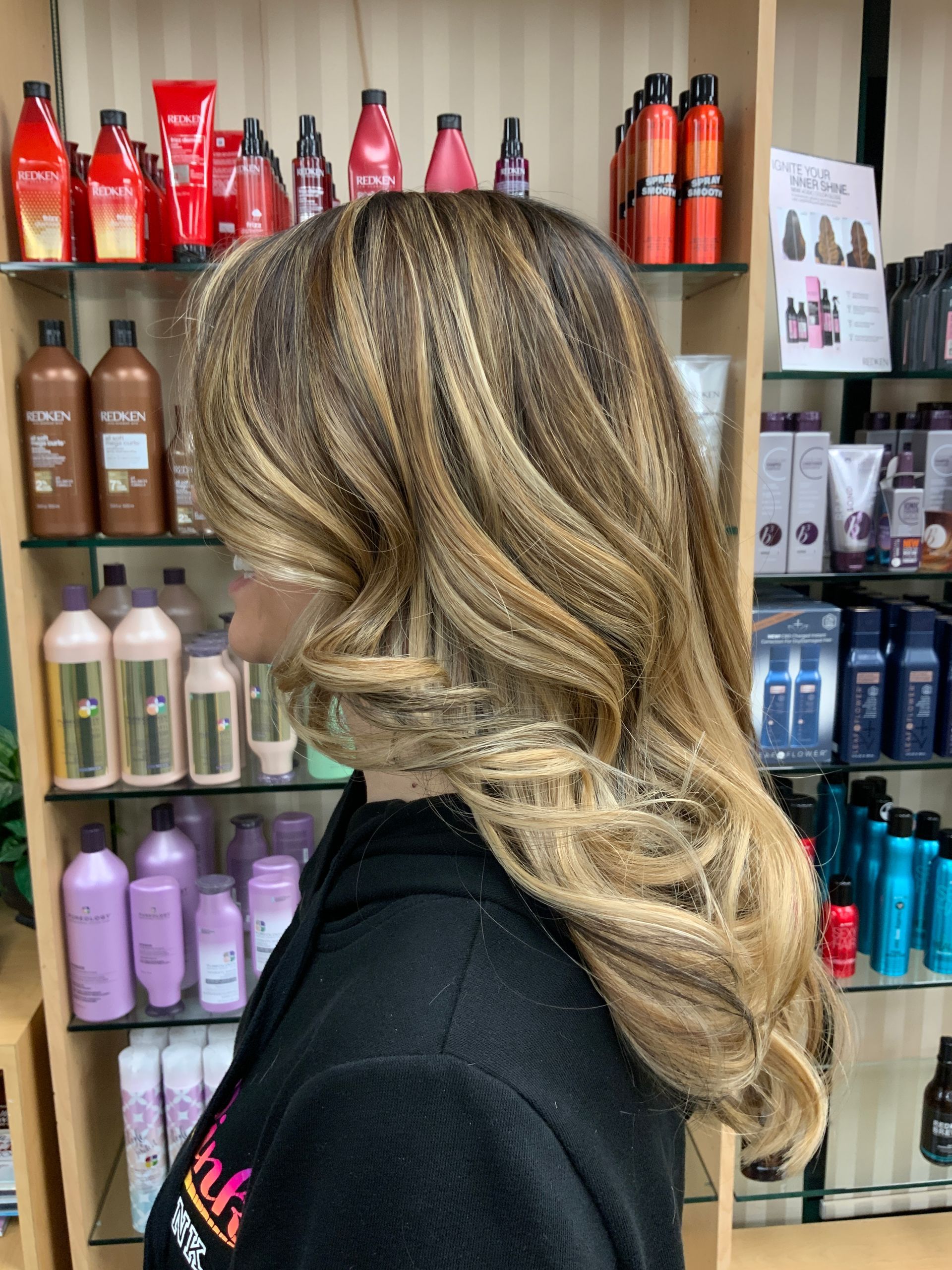 A woman is standing in front of a shelf full of hair products.