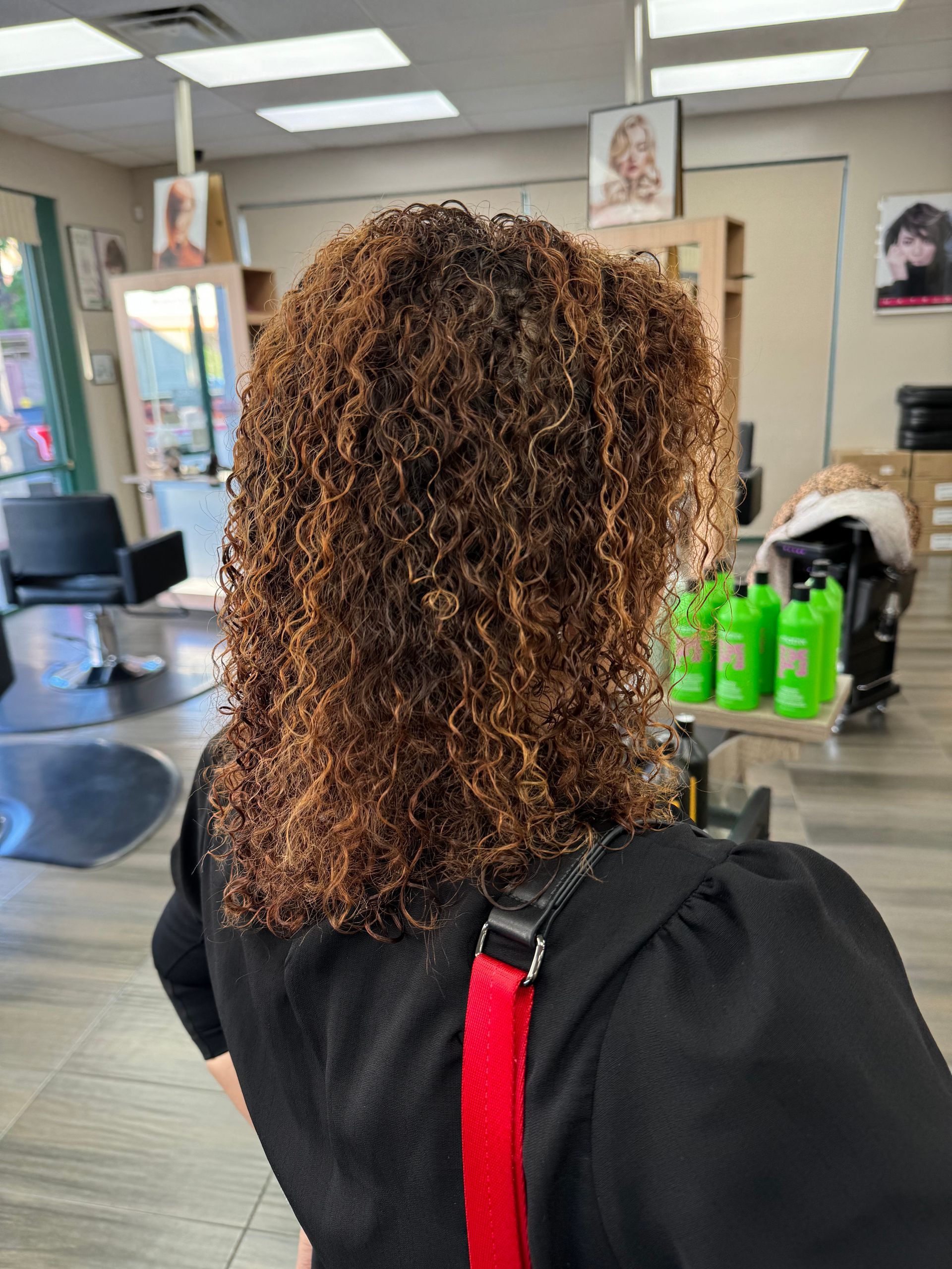 A woman with curly hair is standing in a salon.