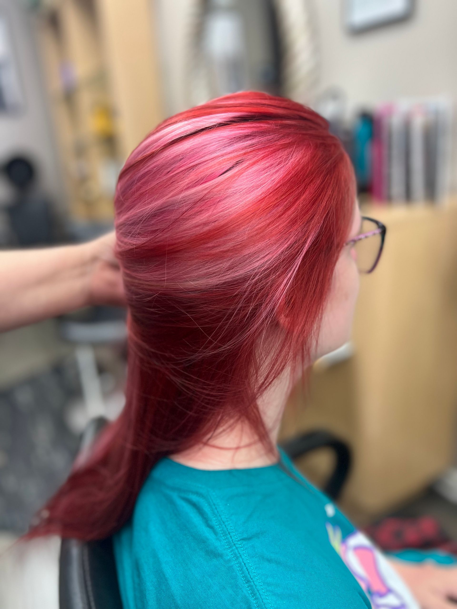 A woman with red hair is getting her hair done at a salon.