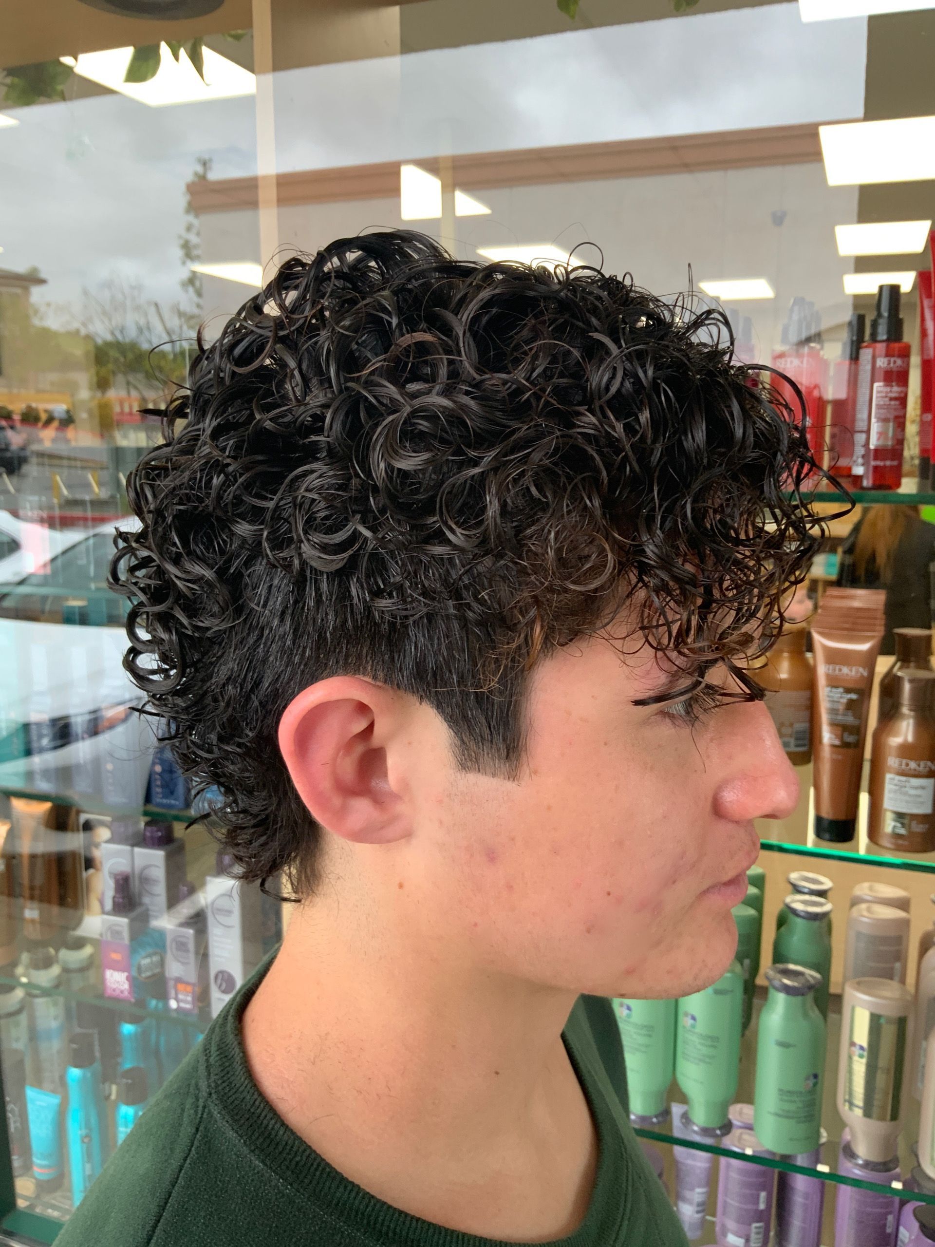 A man with curly hair is standing in front of a display of hair products.