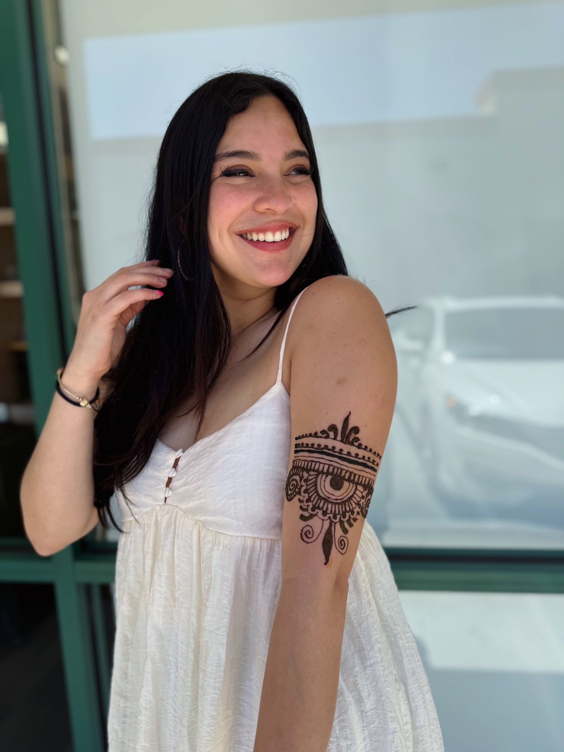 A woman in a white dress has a tattoo on her arm.