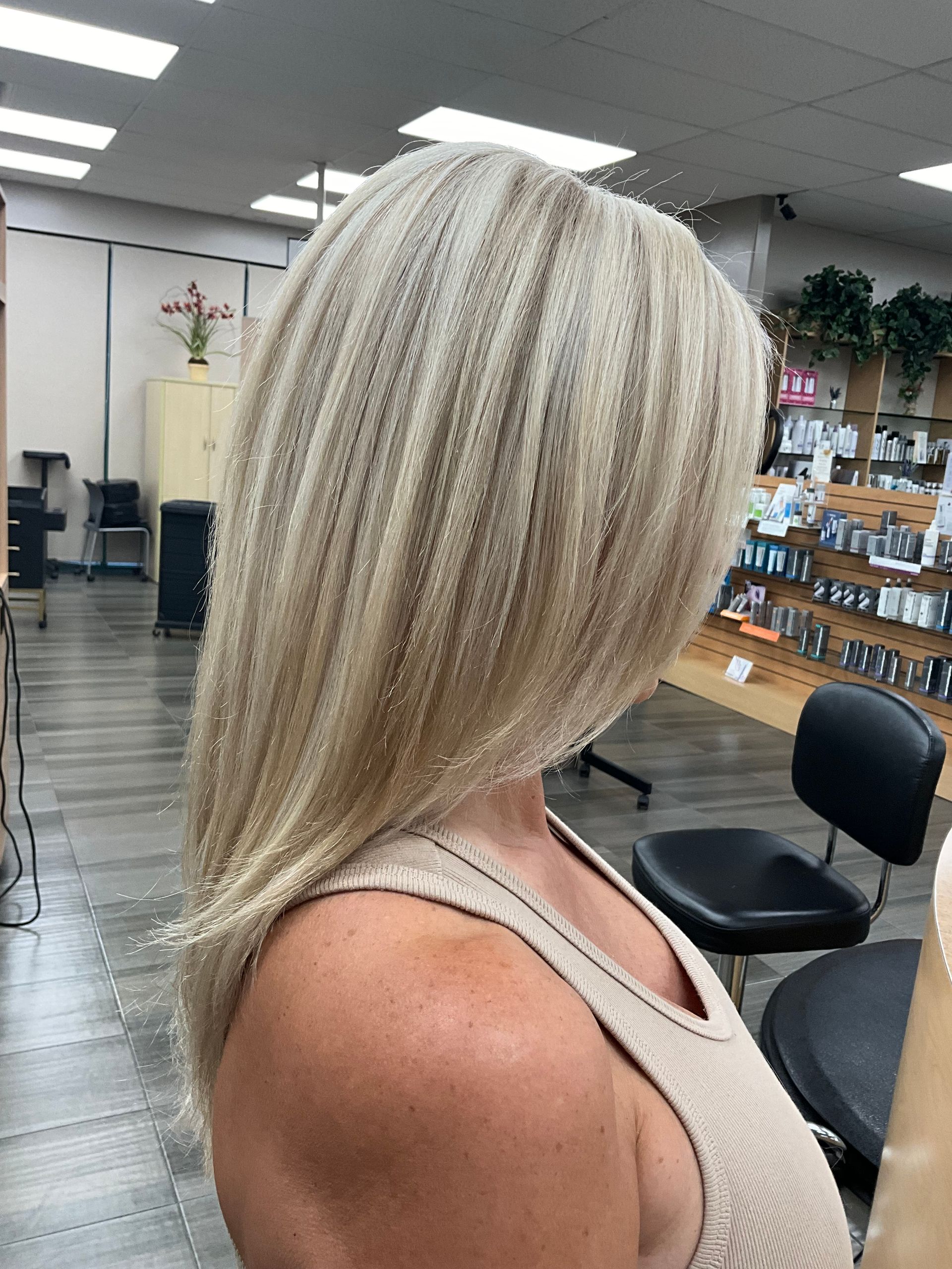 A woman with blonde hair is sitting in a chair in a salon.
