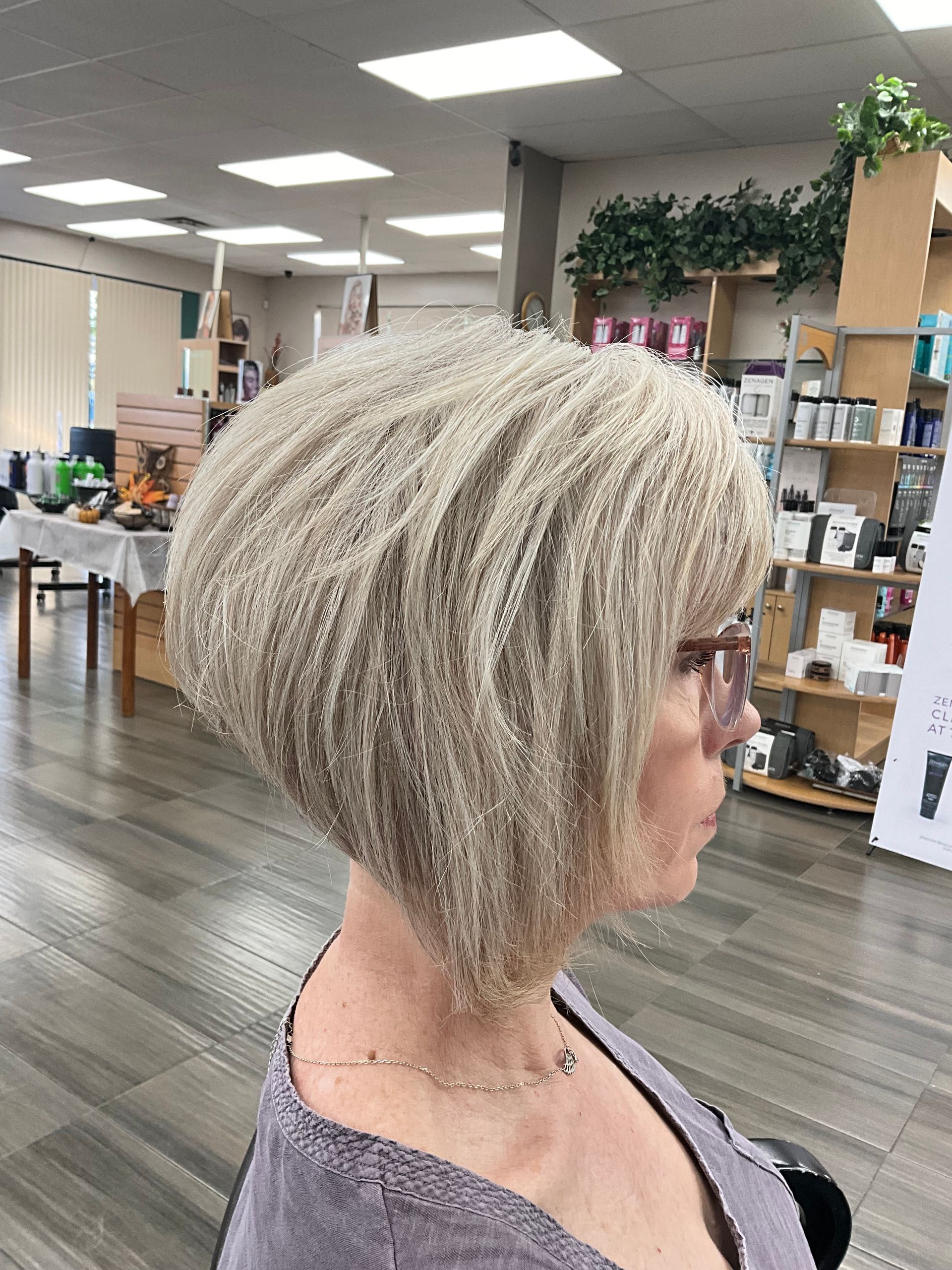 A woman with blonde hair and glasses is getting her hair cut in a salon.