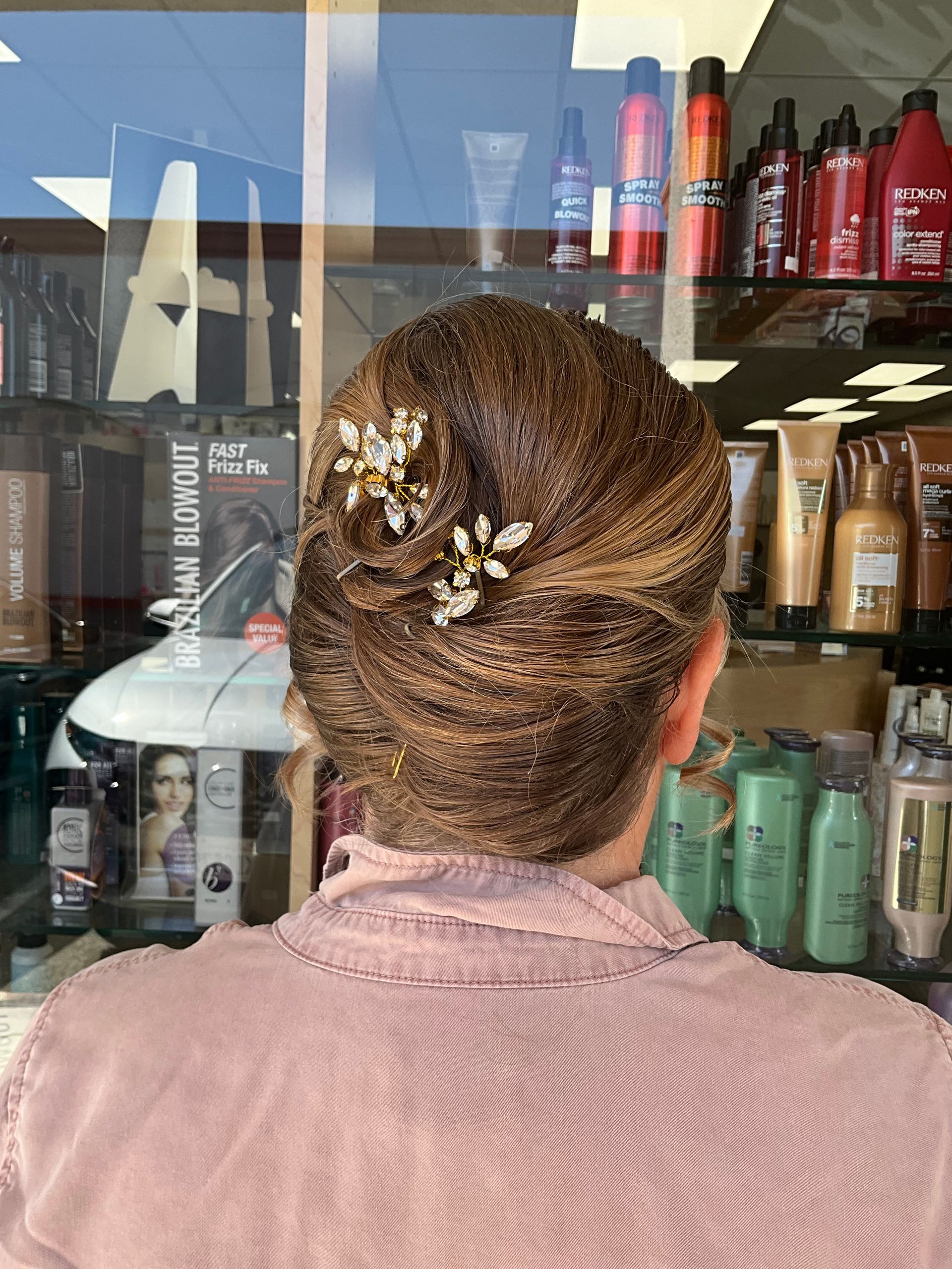 A woman with her hair in a bun is standing in a salon.