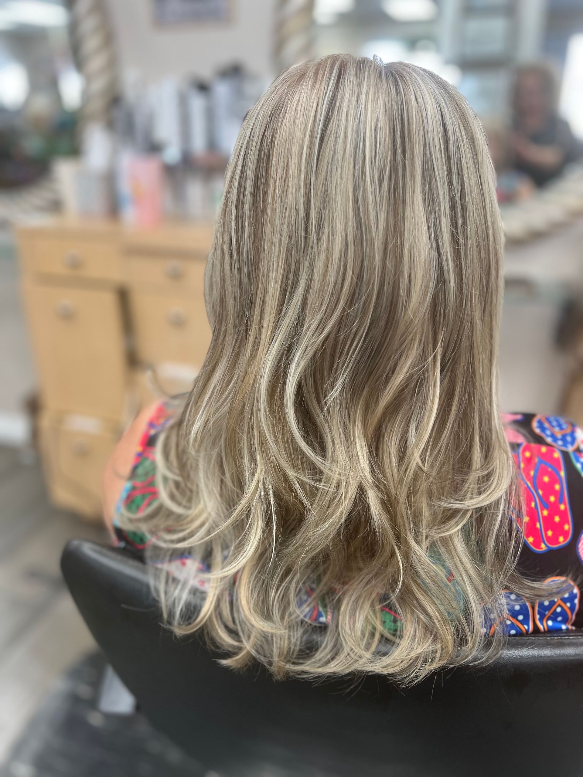 A woman is sitting in a chair with her hair in a salon.