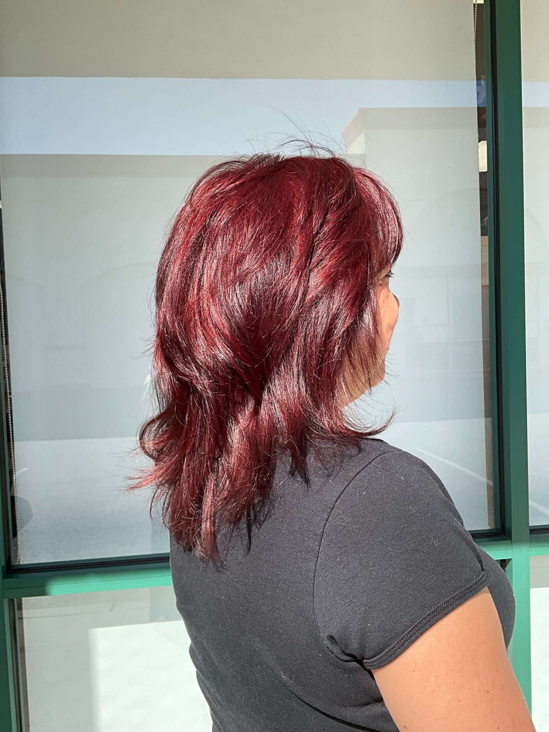 A woman with red hair is standing in front of a window.