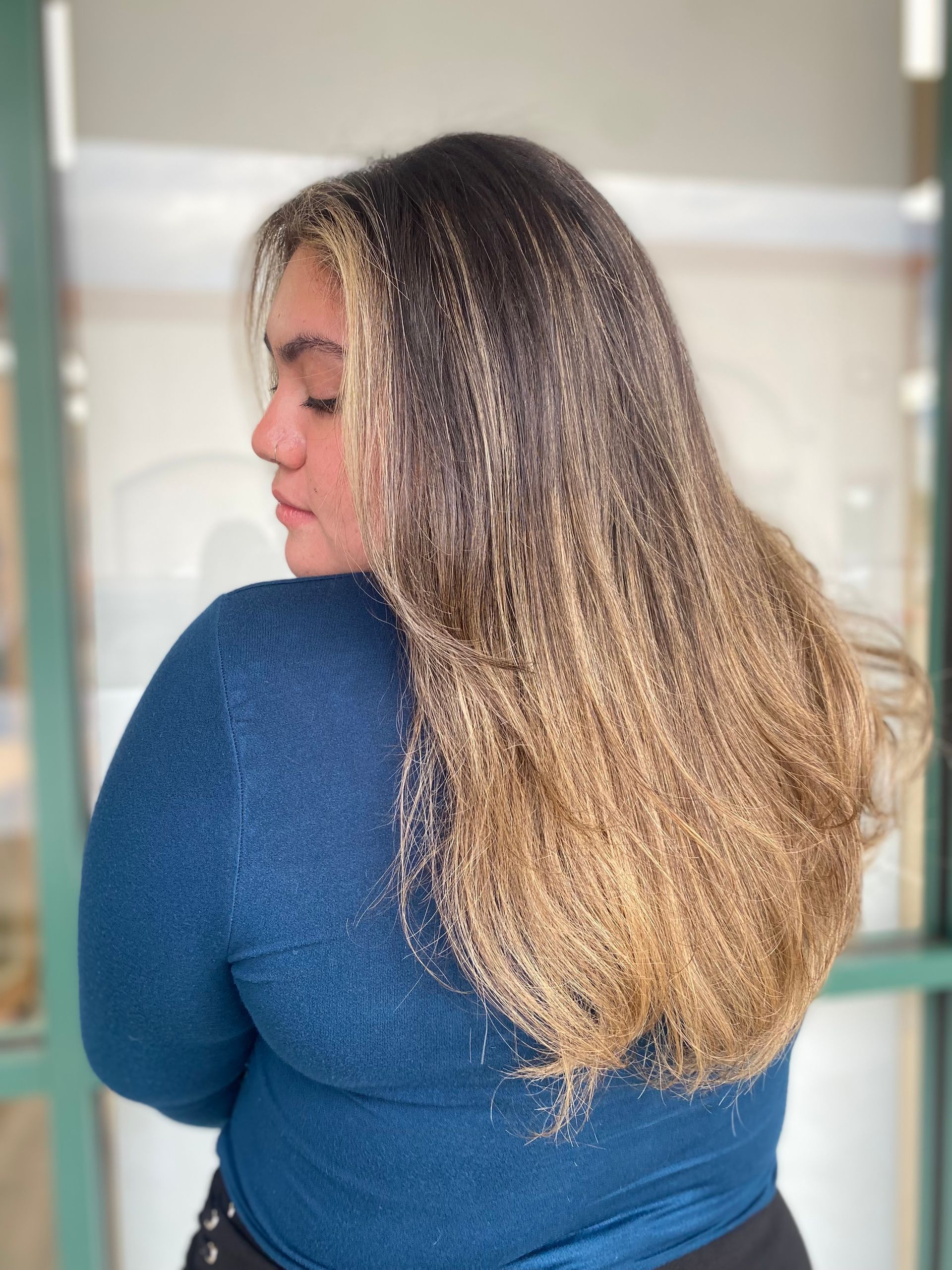 A woman with long hair is wearing a blue sweater.
