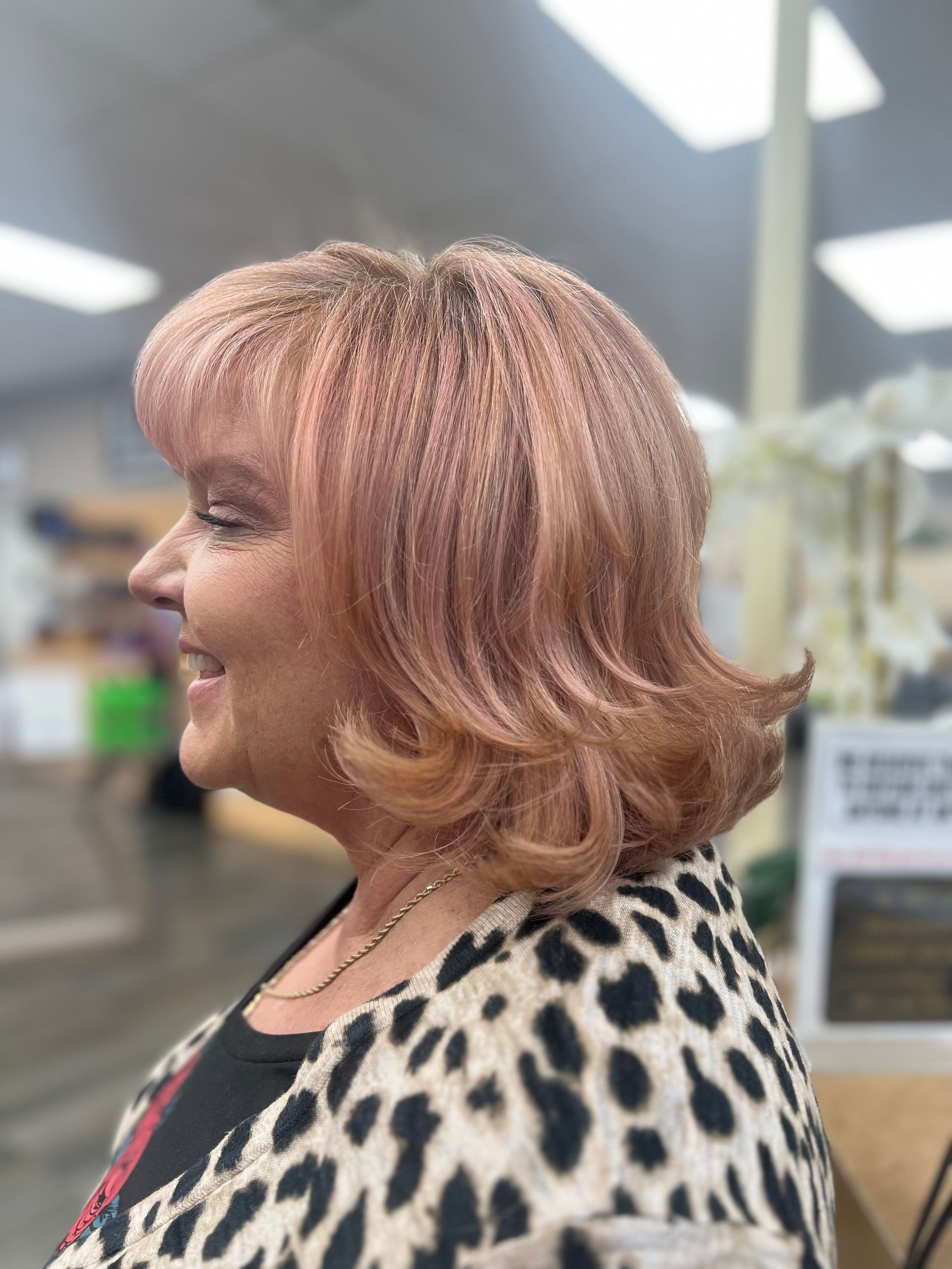 A woman with pink hair is wearing a leopard print shirt.