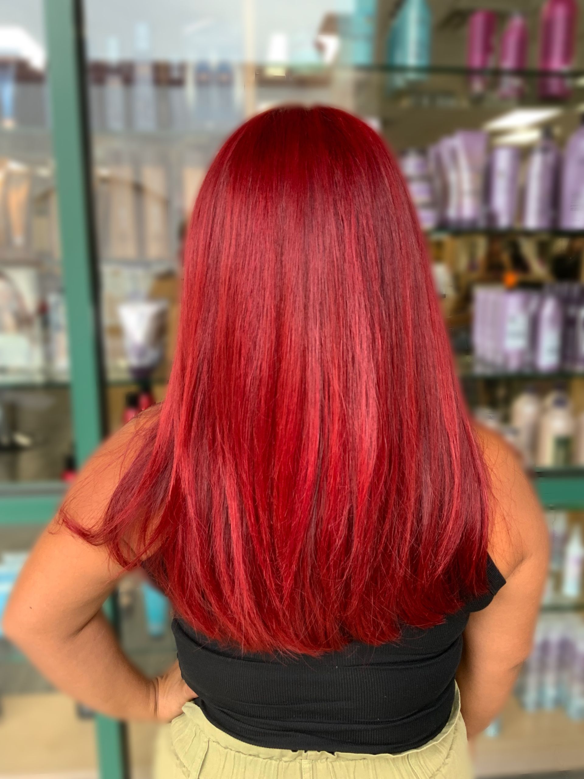 A woman with long red hair is standing in front of a store.