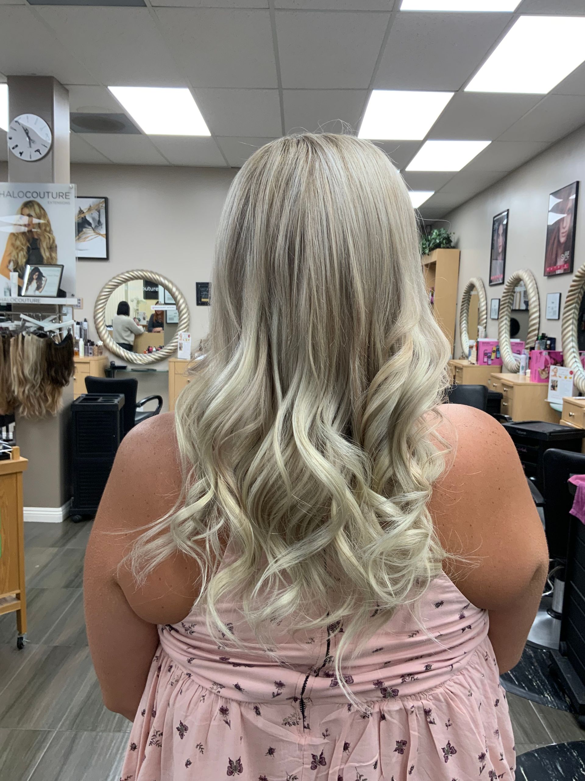 A woman in a pink dress is standing in a salon with her back to the camera.