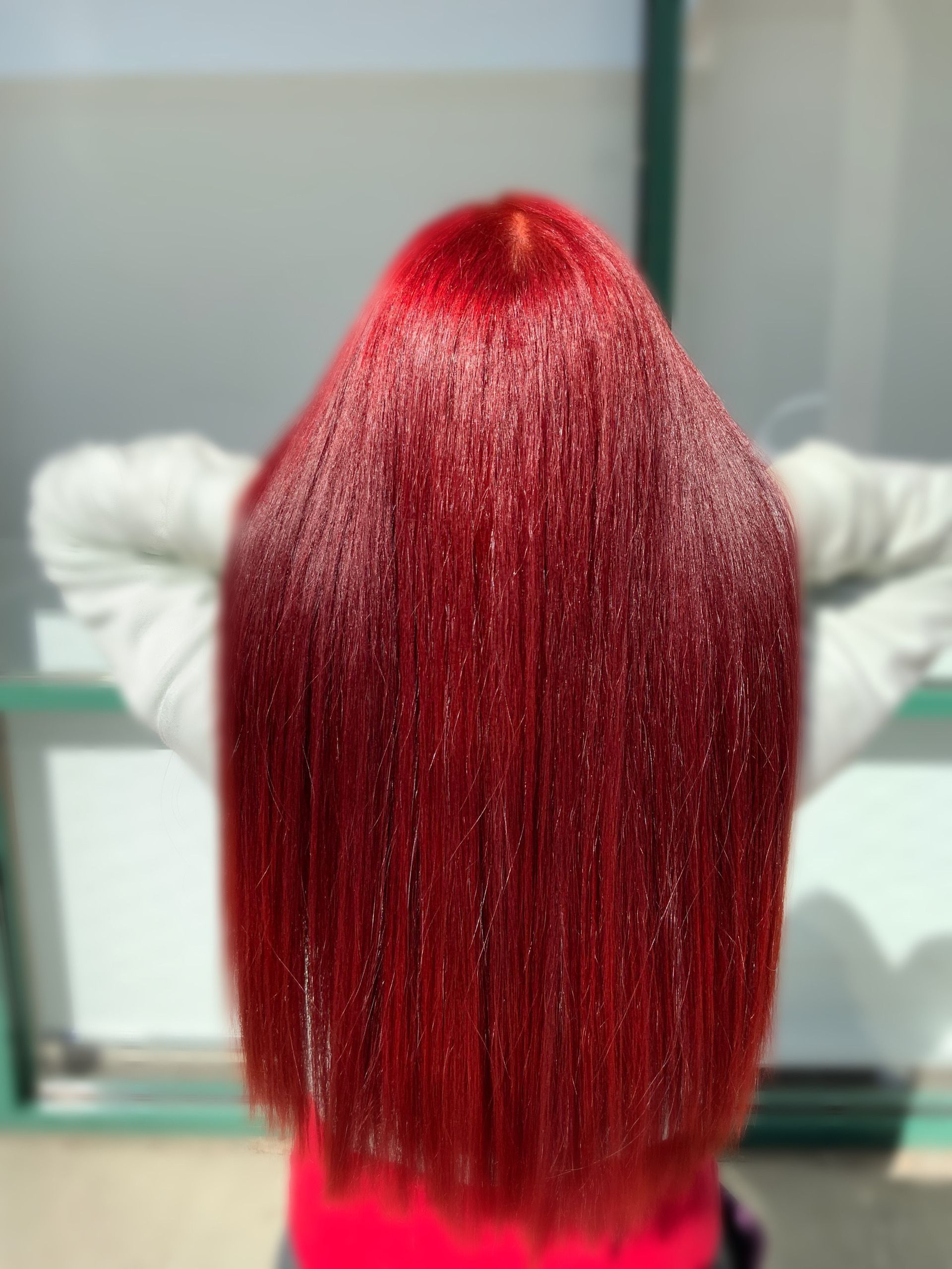 A woman with red hair is sitting with her hands behind her head.
