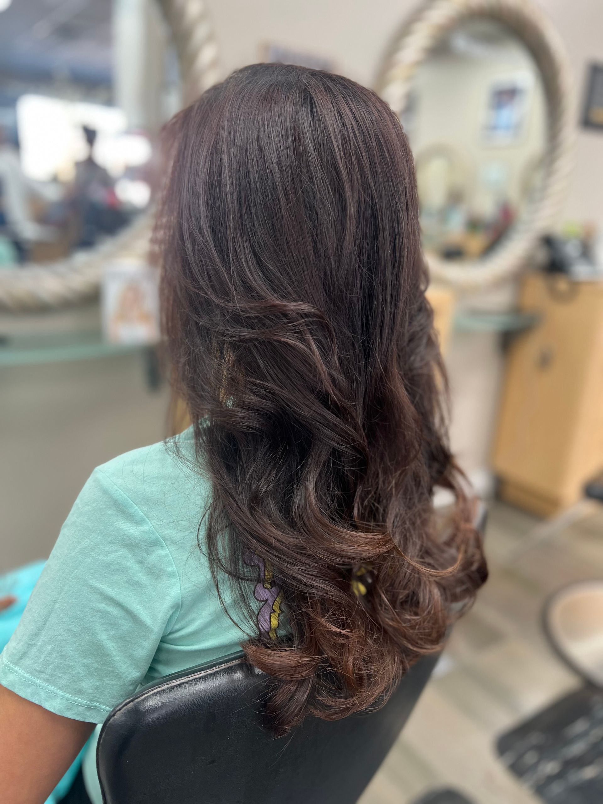 A woman is sitting in a chair with her hair in a salon.