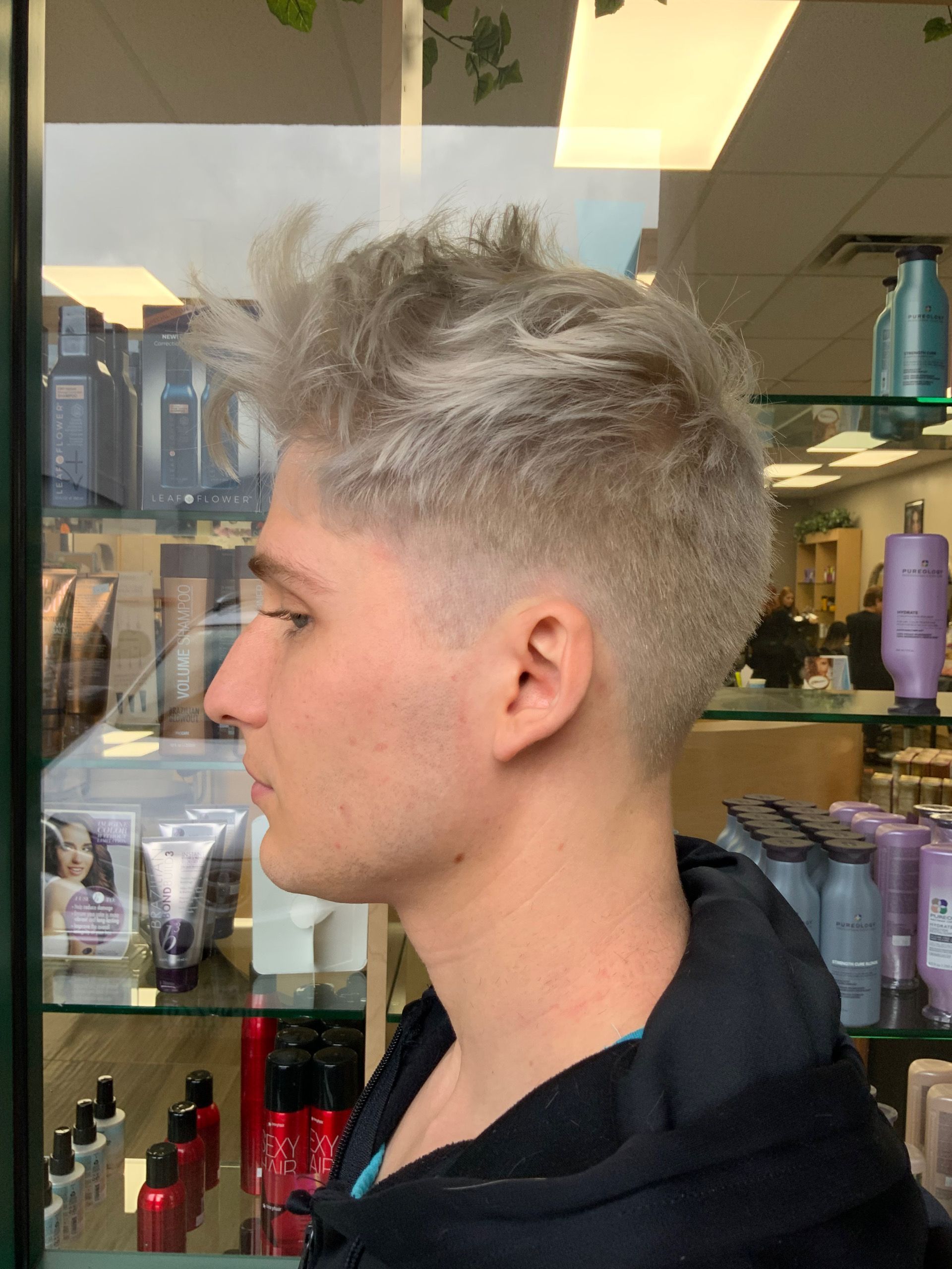 A man with gray hair is standing in front of a display of hair products