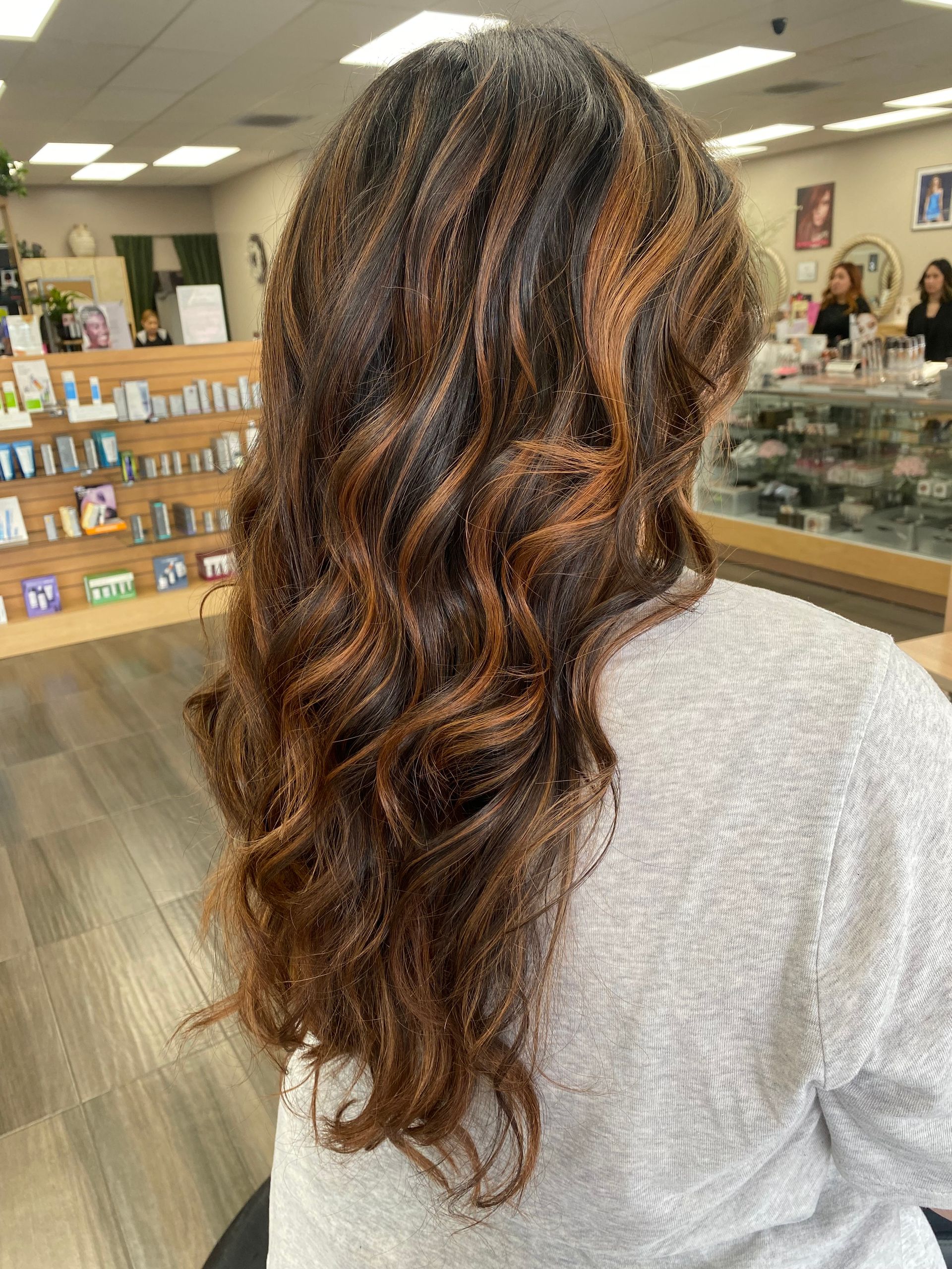 A woman with long curly hair is sitting in a chair in a store.