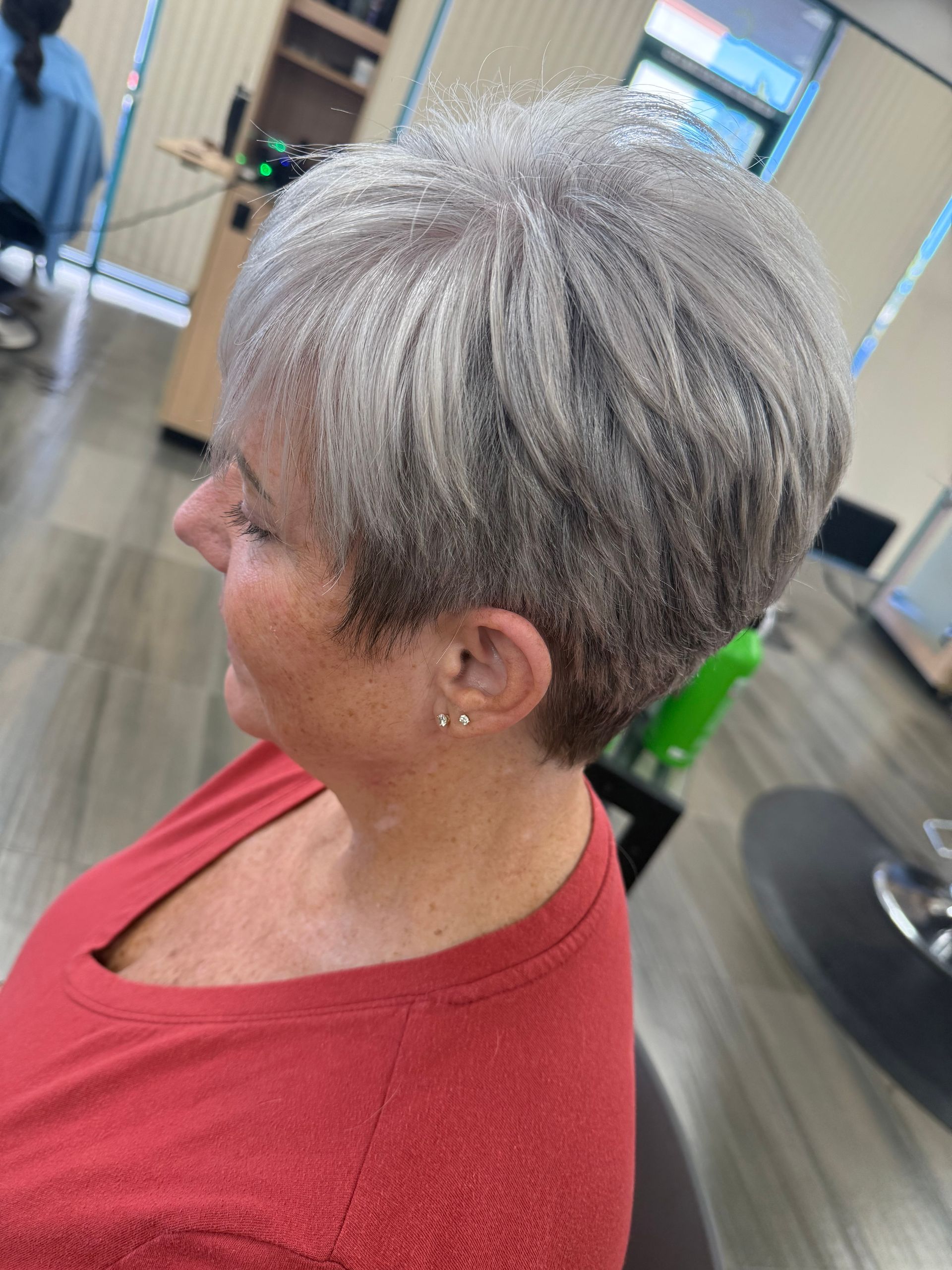 A woman with short gray hair is sitting in a hair salon.