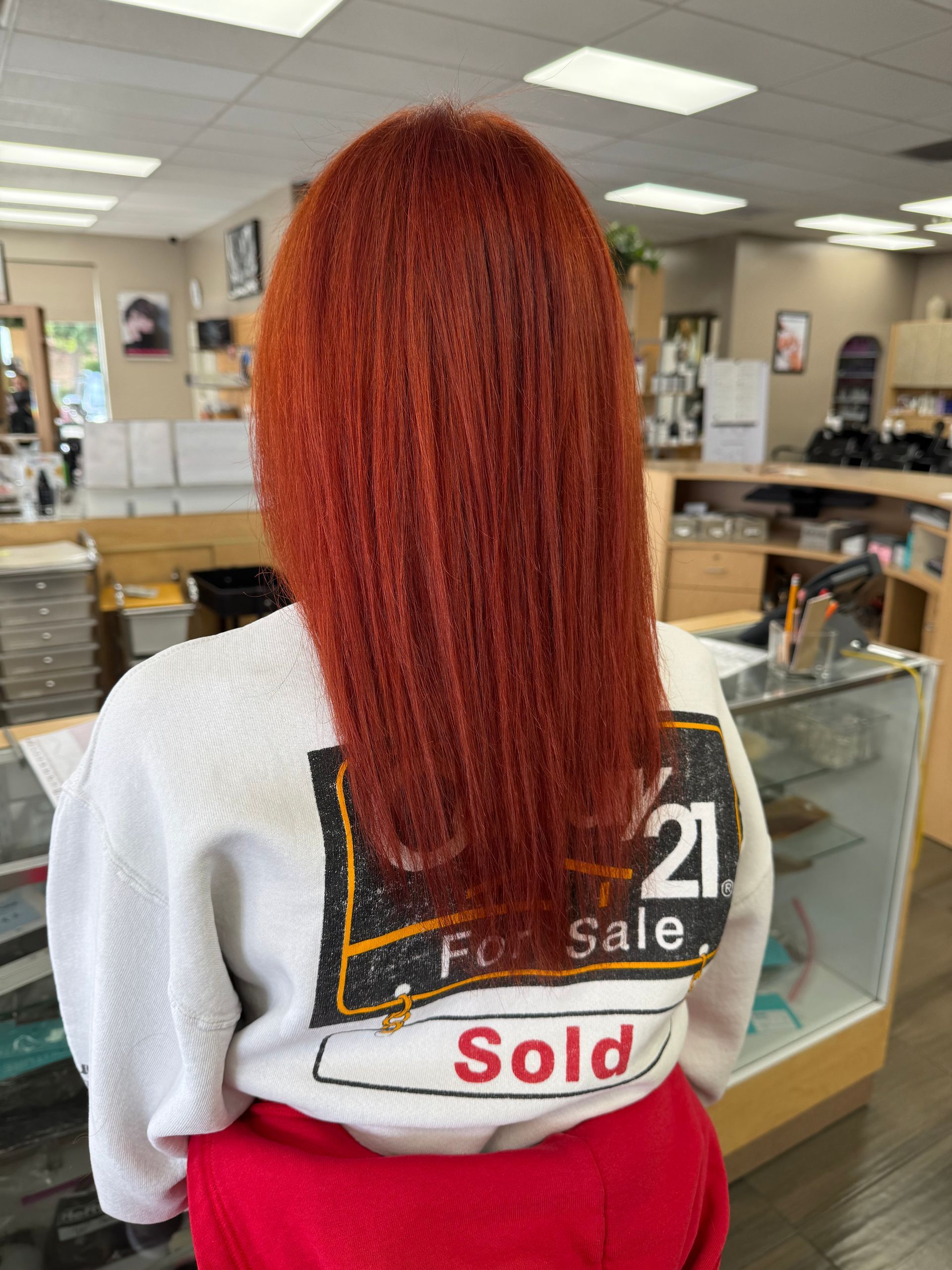 A woman with red hair is wearing a sweatshirt that says sold on the back.