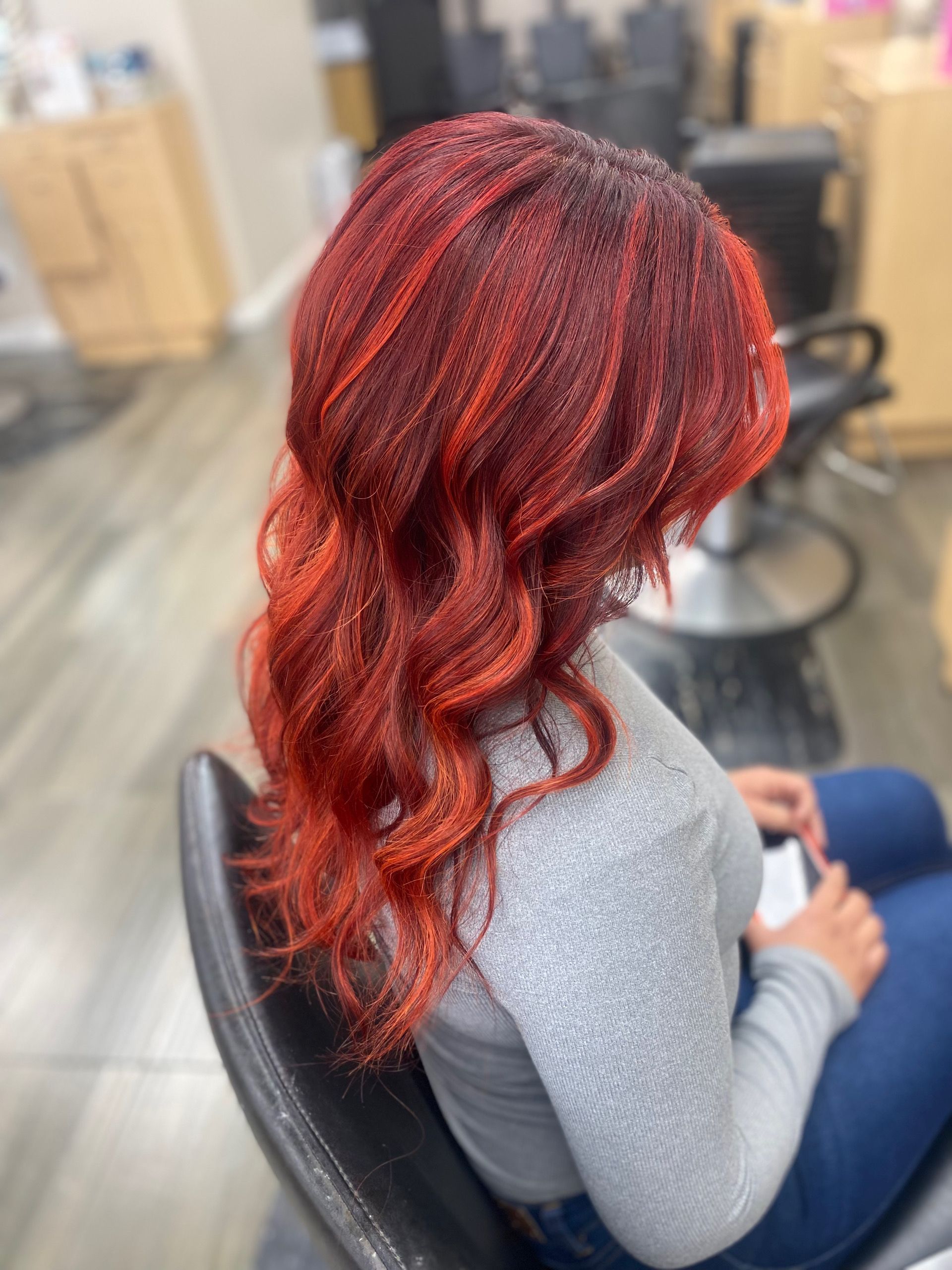 A woman with red hair is sitting in a chair in a salon.