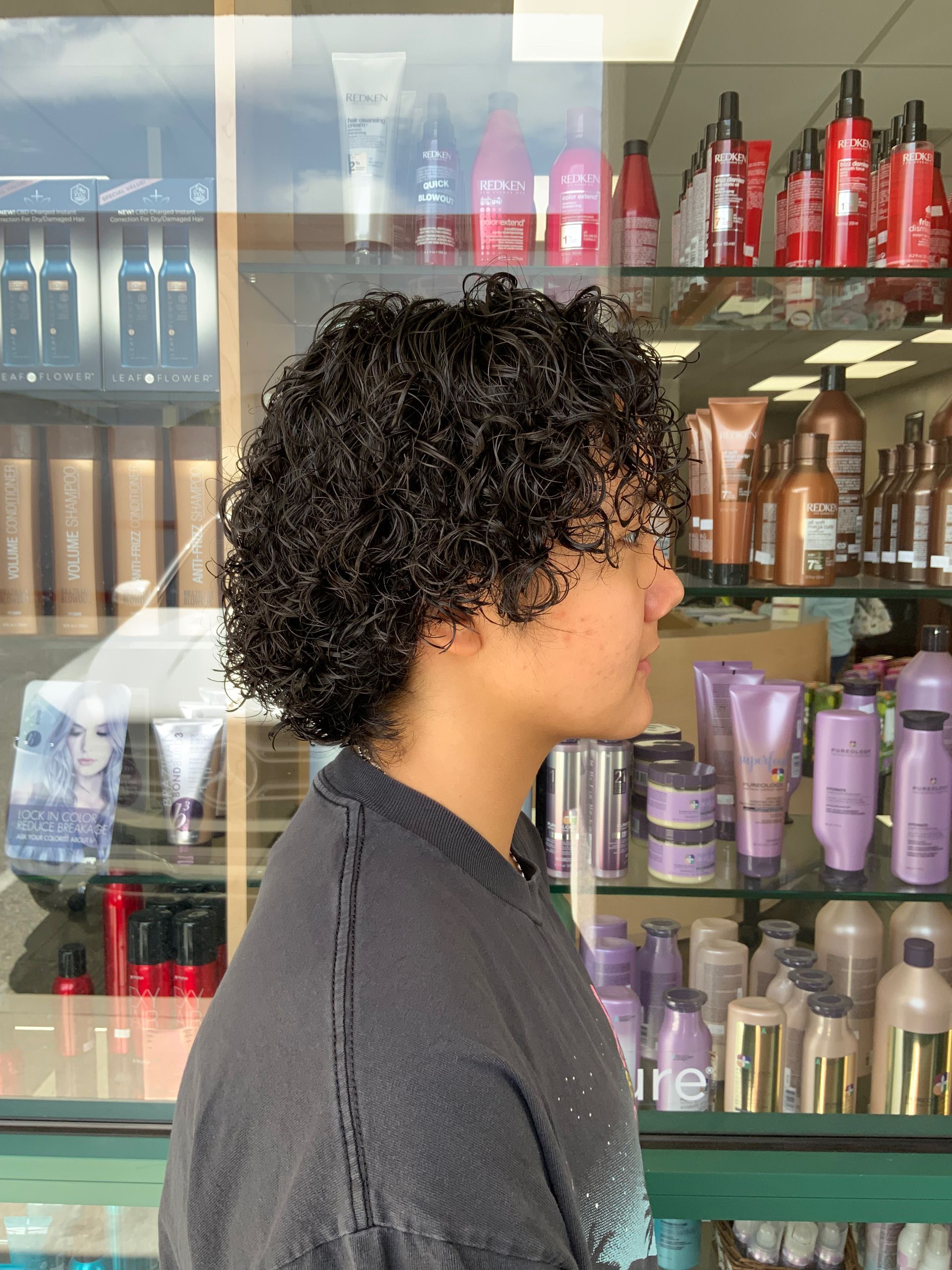 A woman with curly hair is standing in front of a display of hair products.