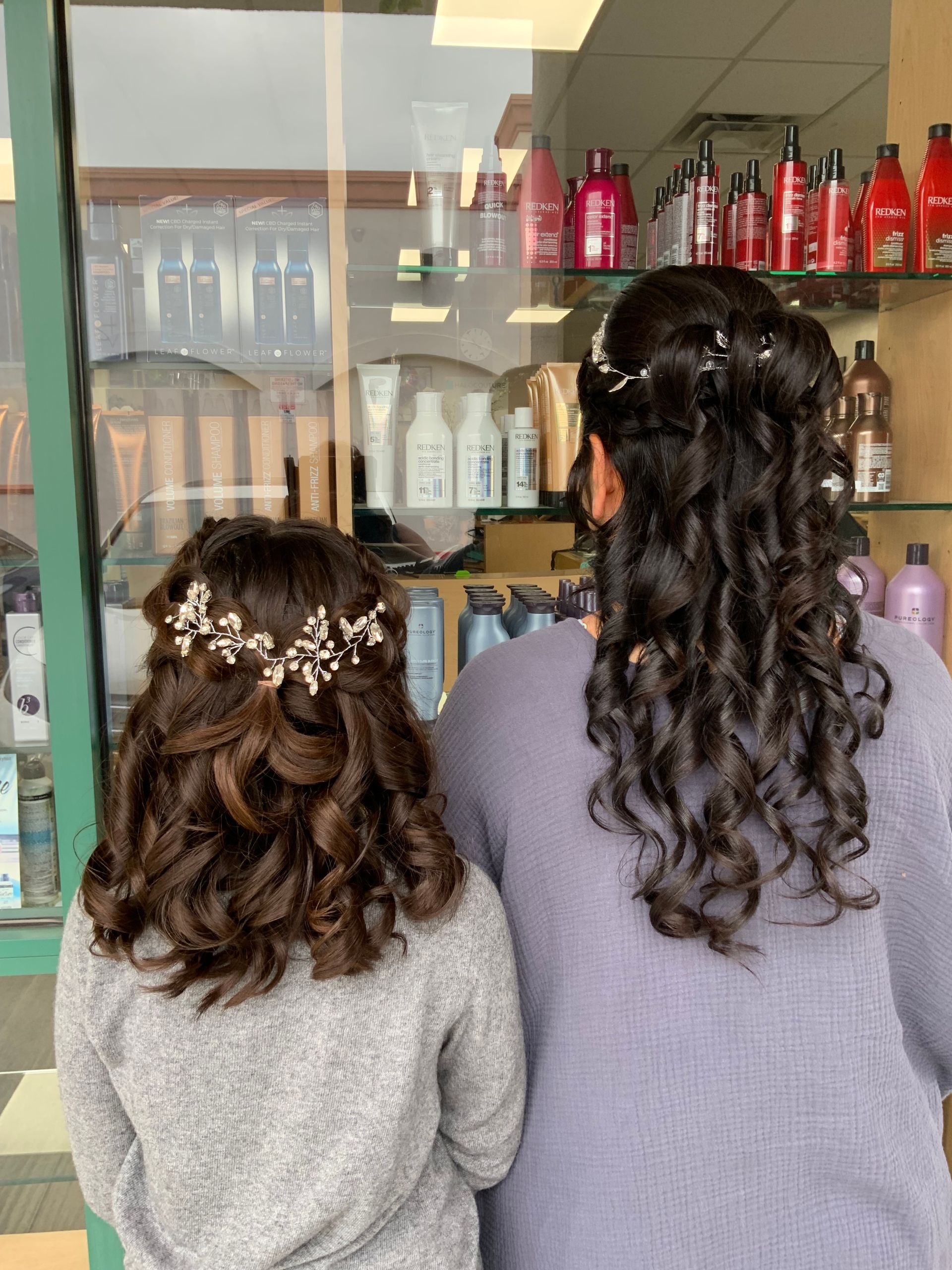 A woman and a little girl are standing next to each other in a salon.